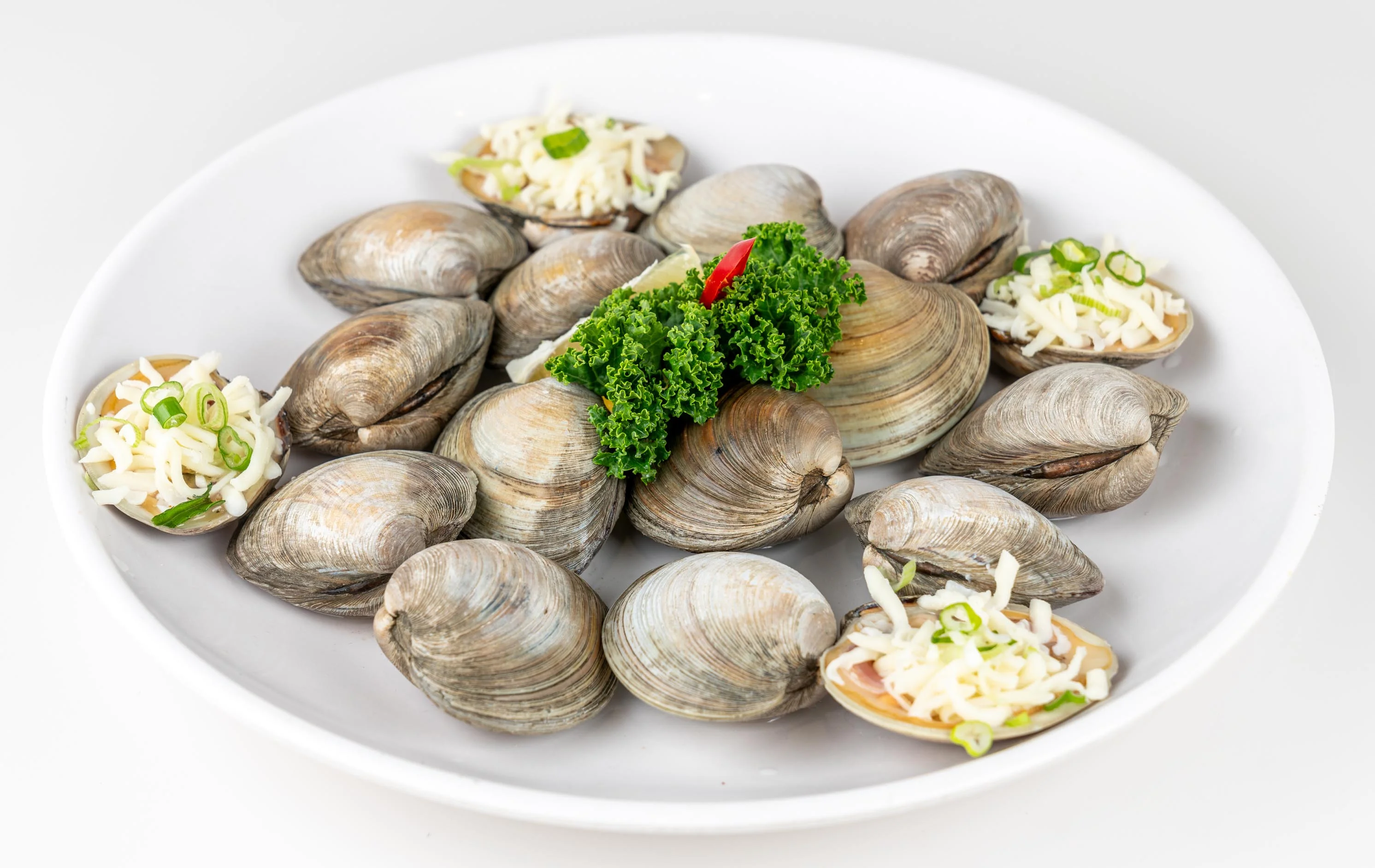 Baked clams with cheese and herbs on a white plate