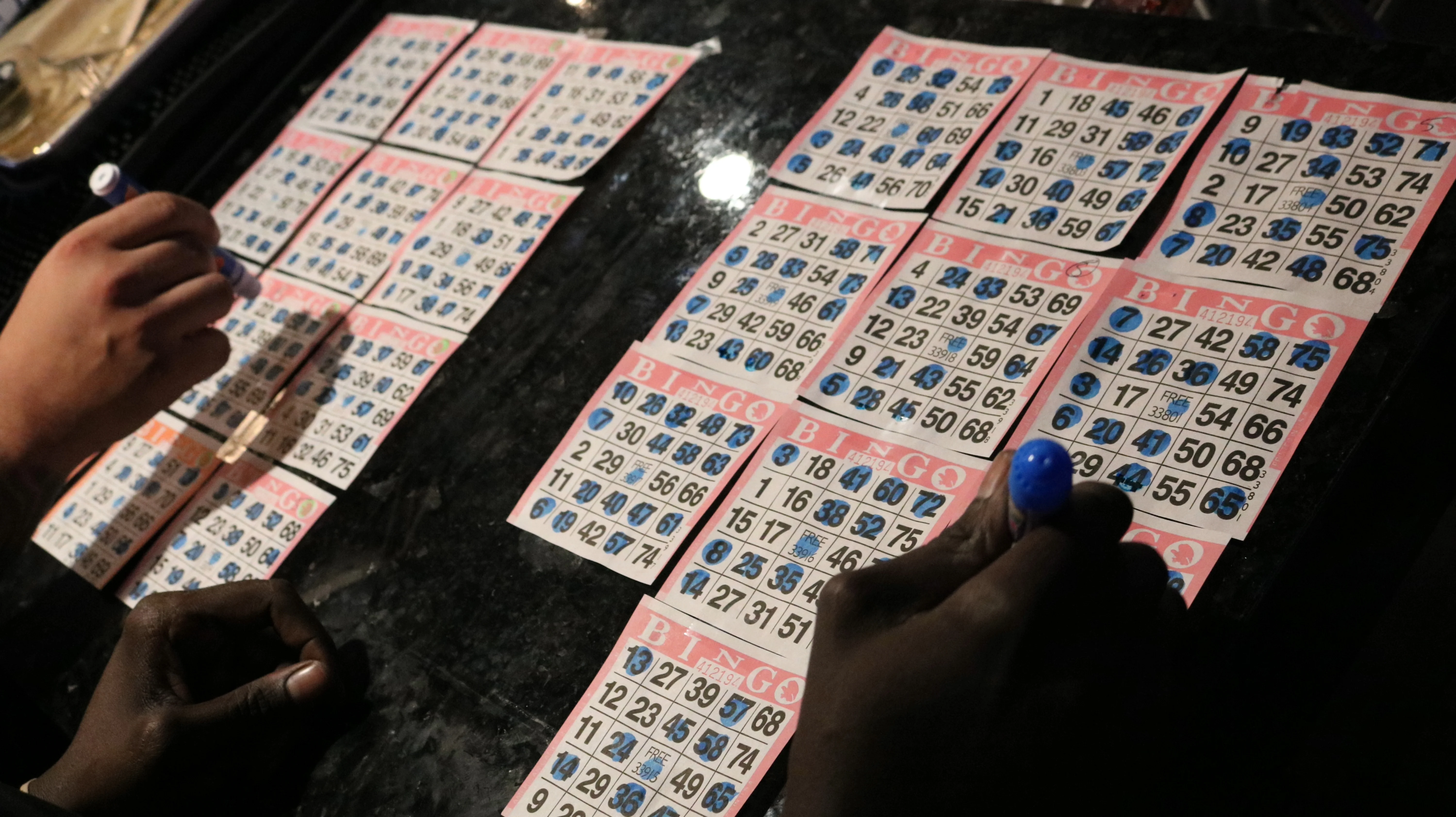 Bingo cards and players marking numbers at a game night