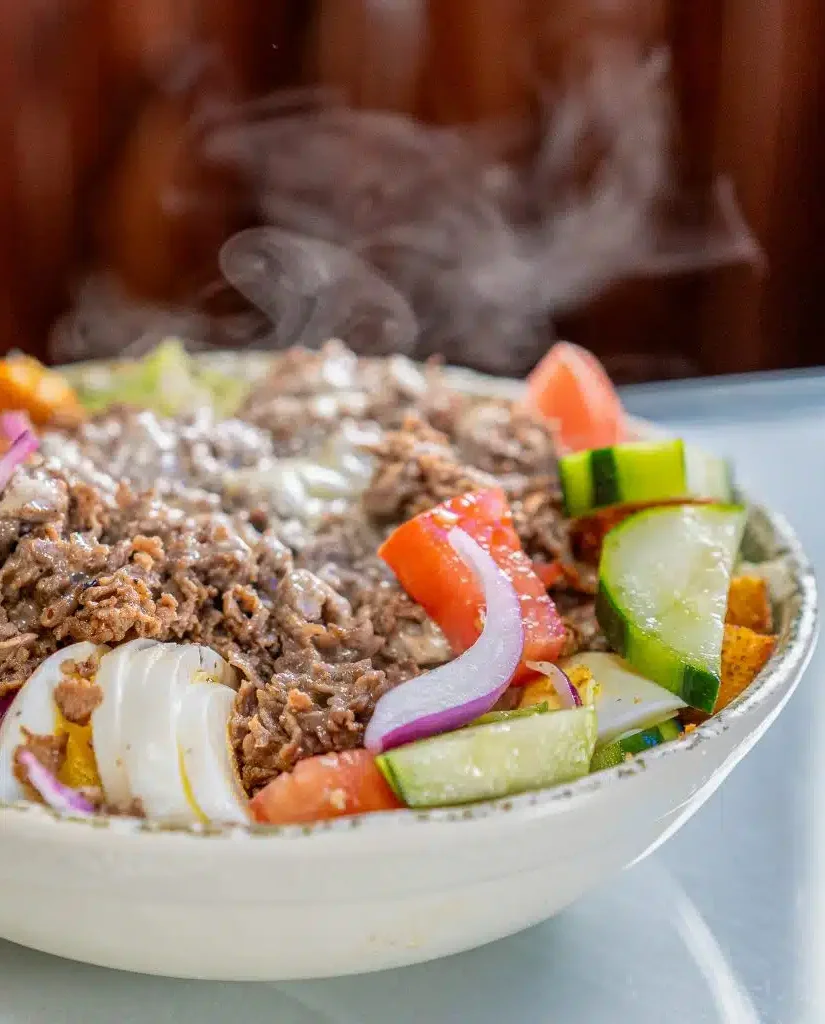  Salad bowl with shredded beef, tomato, cucumber, onion, and shredded cheese.