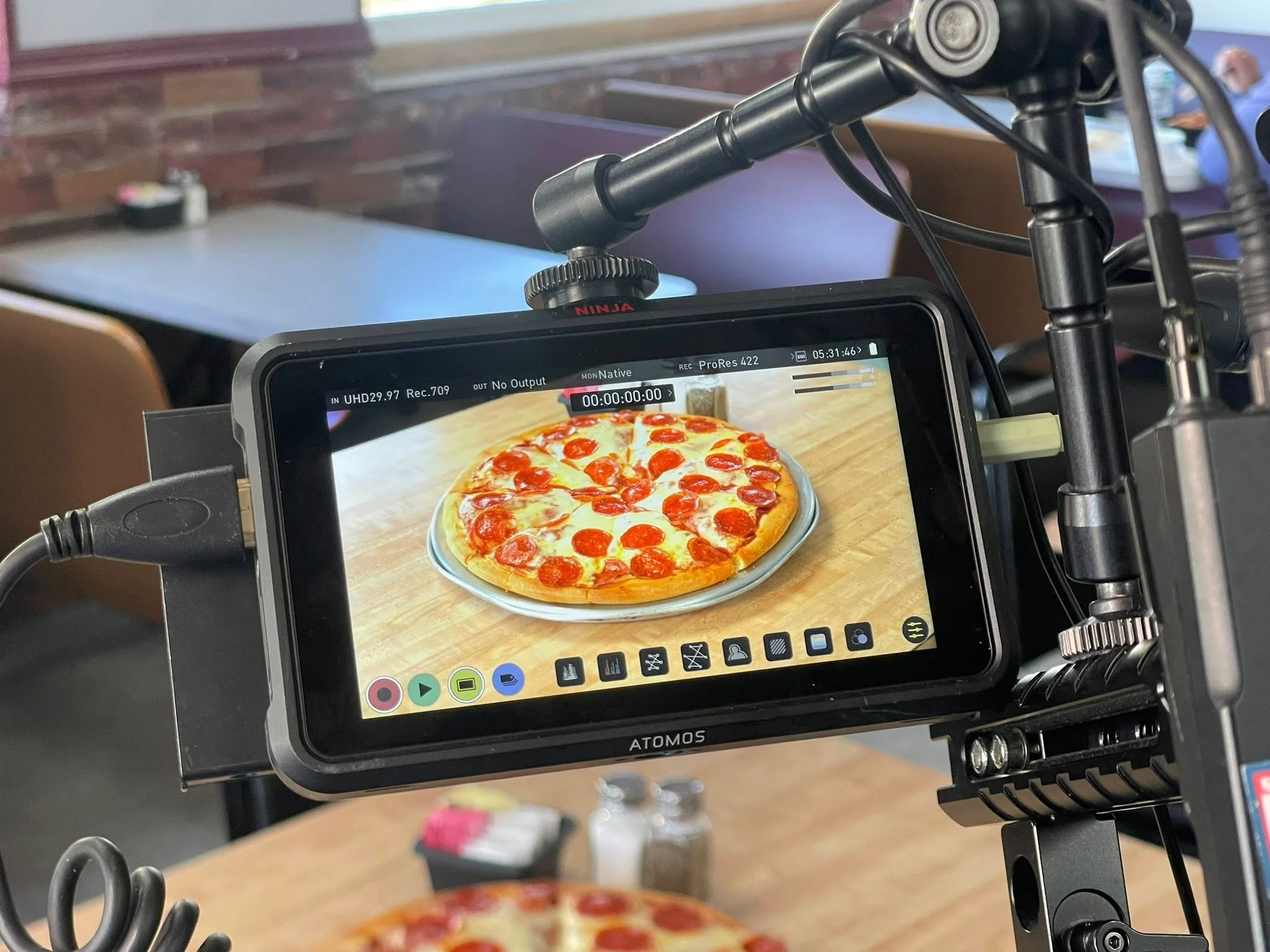 A camera monitor displaying a well-presented pizza on a table, ready for filming.