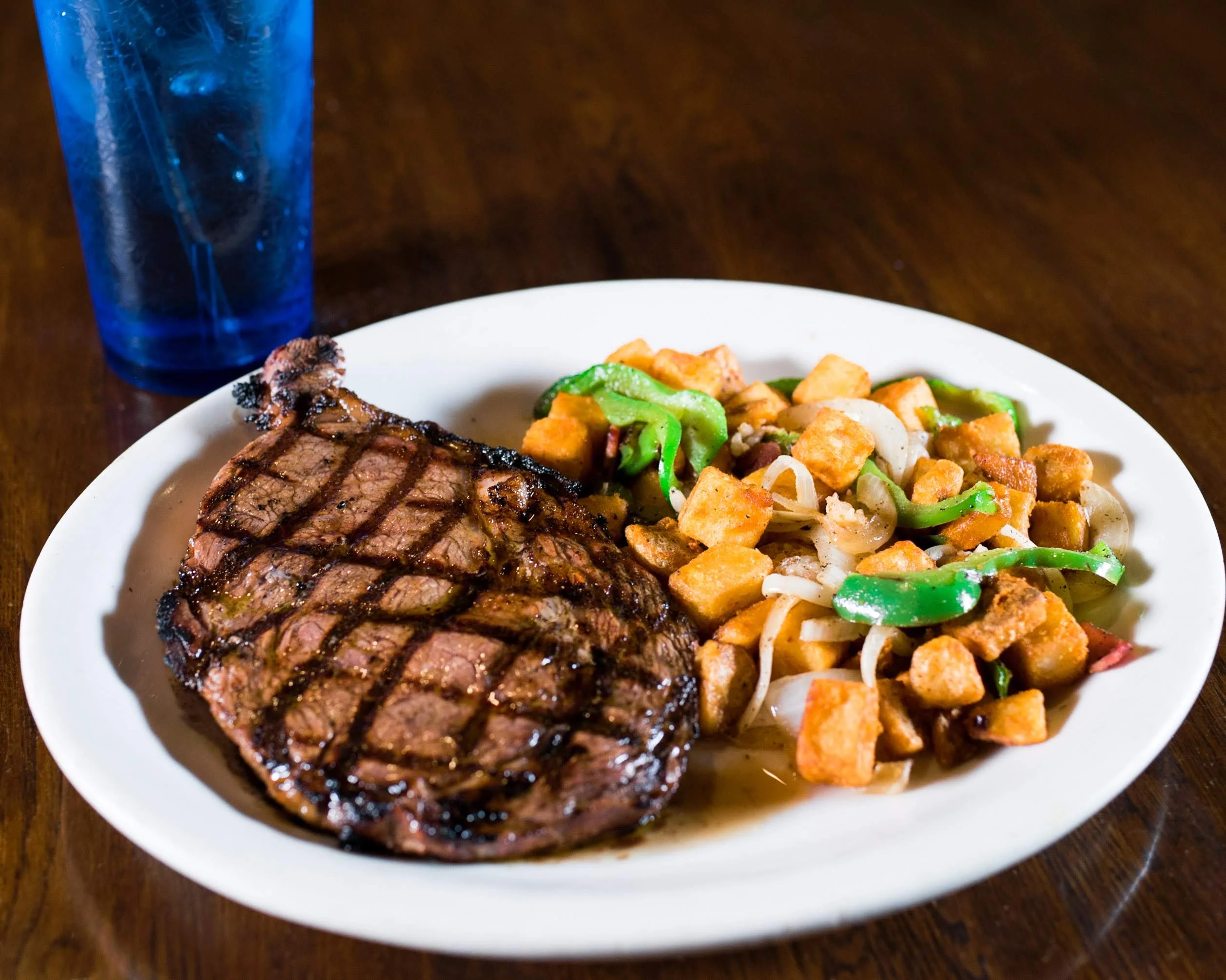 Grilled ribeye steak with seasoned potatoes and peppers
