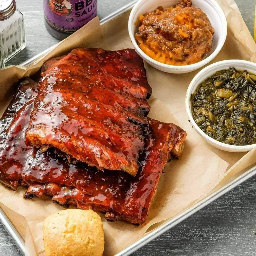 BBQ rib plate from VooDoo BBQ in Pensacola with glazed ribs, sweet potato casserole, greens, and cornbread.