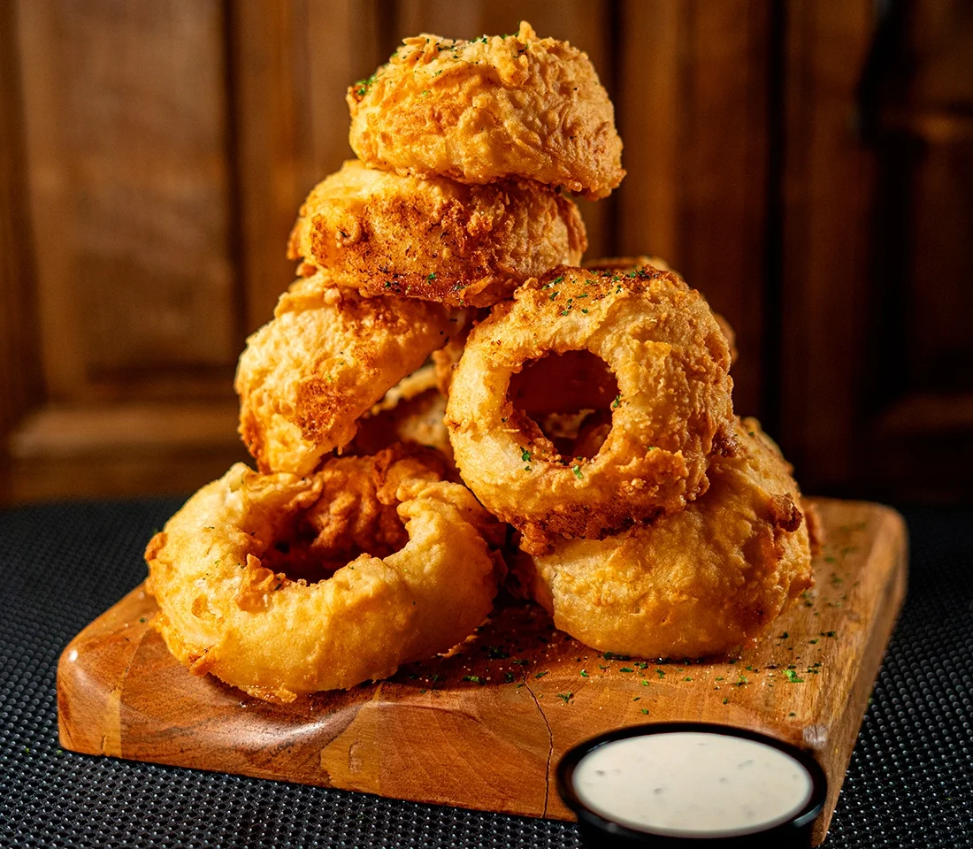 Crispy onion rings stacked on a wooden board