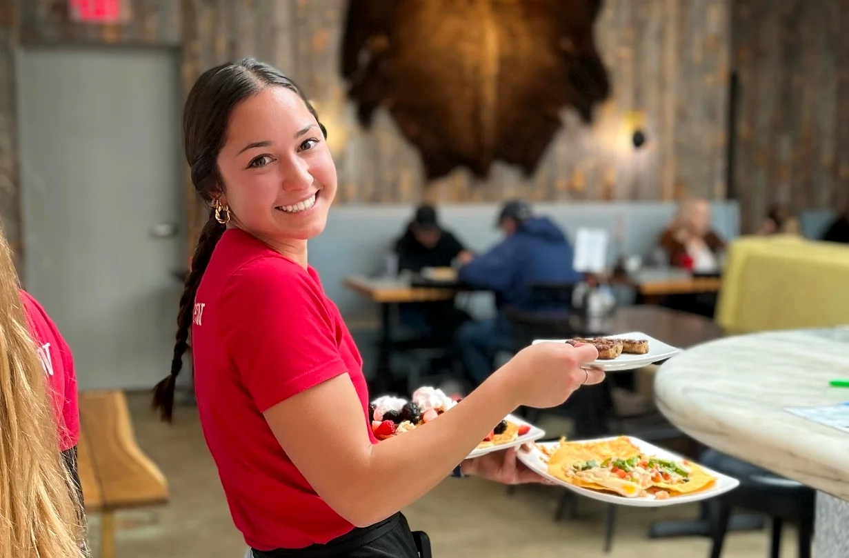 Happy smiling server holding multiple plates of delicious food