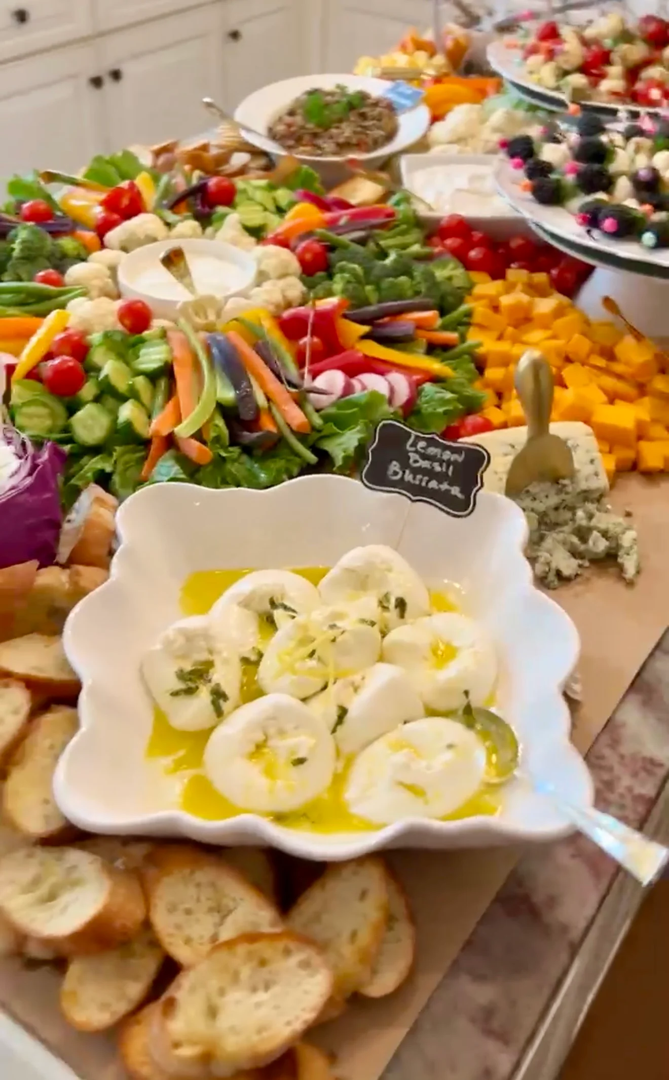 A vibrant spread of fresh vegetables, cheeses, and dips on a buffet table.