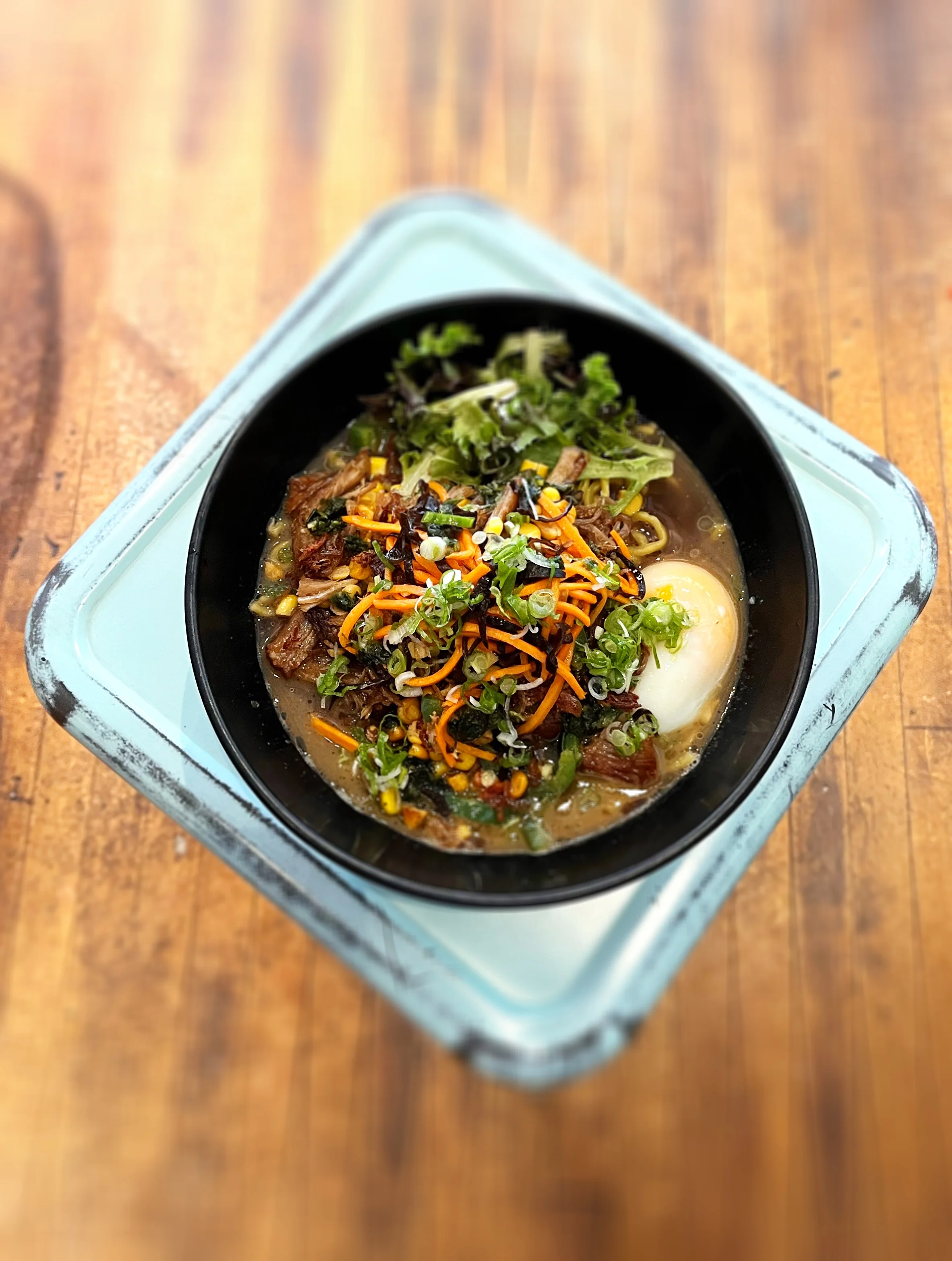 Bowl of Japanese ramen with soft-boiled egg and fresh vegetables