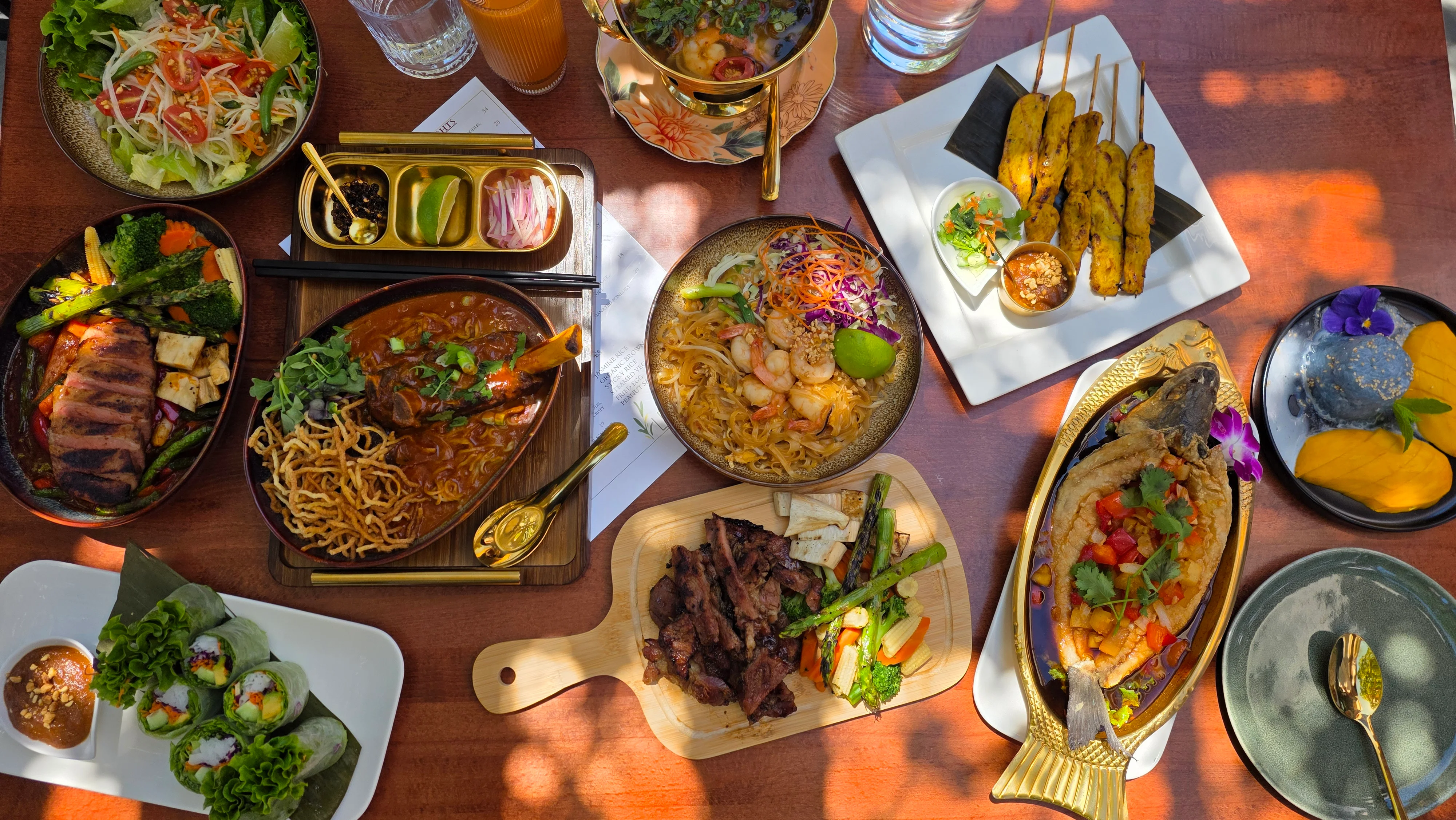 A vibrant spread of various Asian dishes on a wooden table.