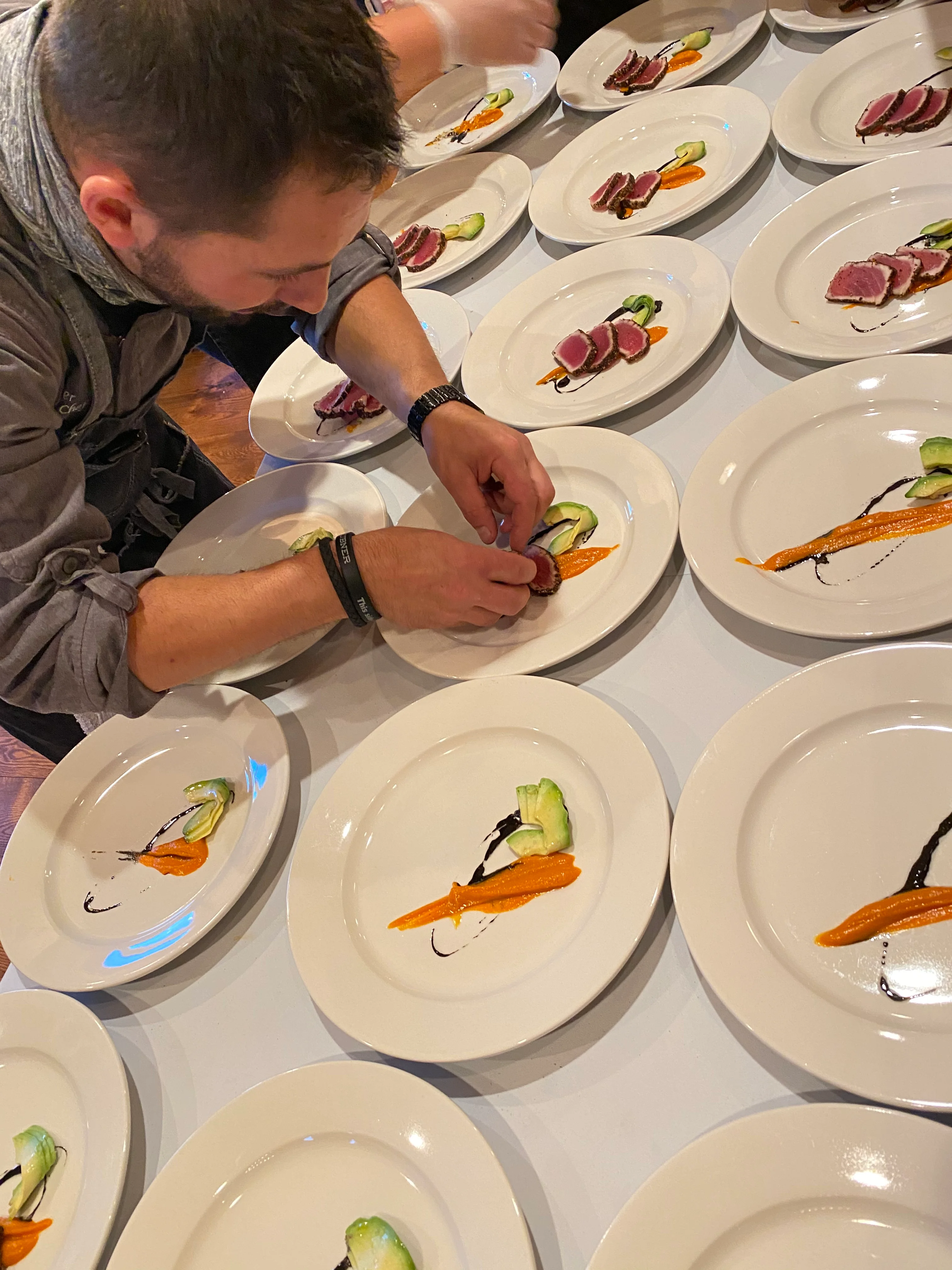 Chef plating gourmet tuna with colorful vegetable garnishes