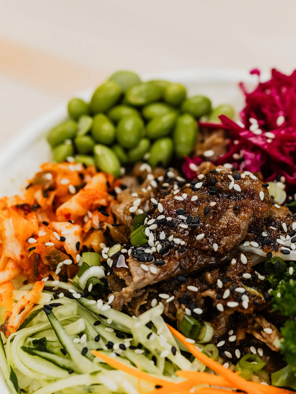 close up image of a pre-made bowl with beef, fresh toppings, and sauce