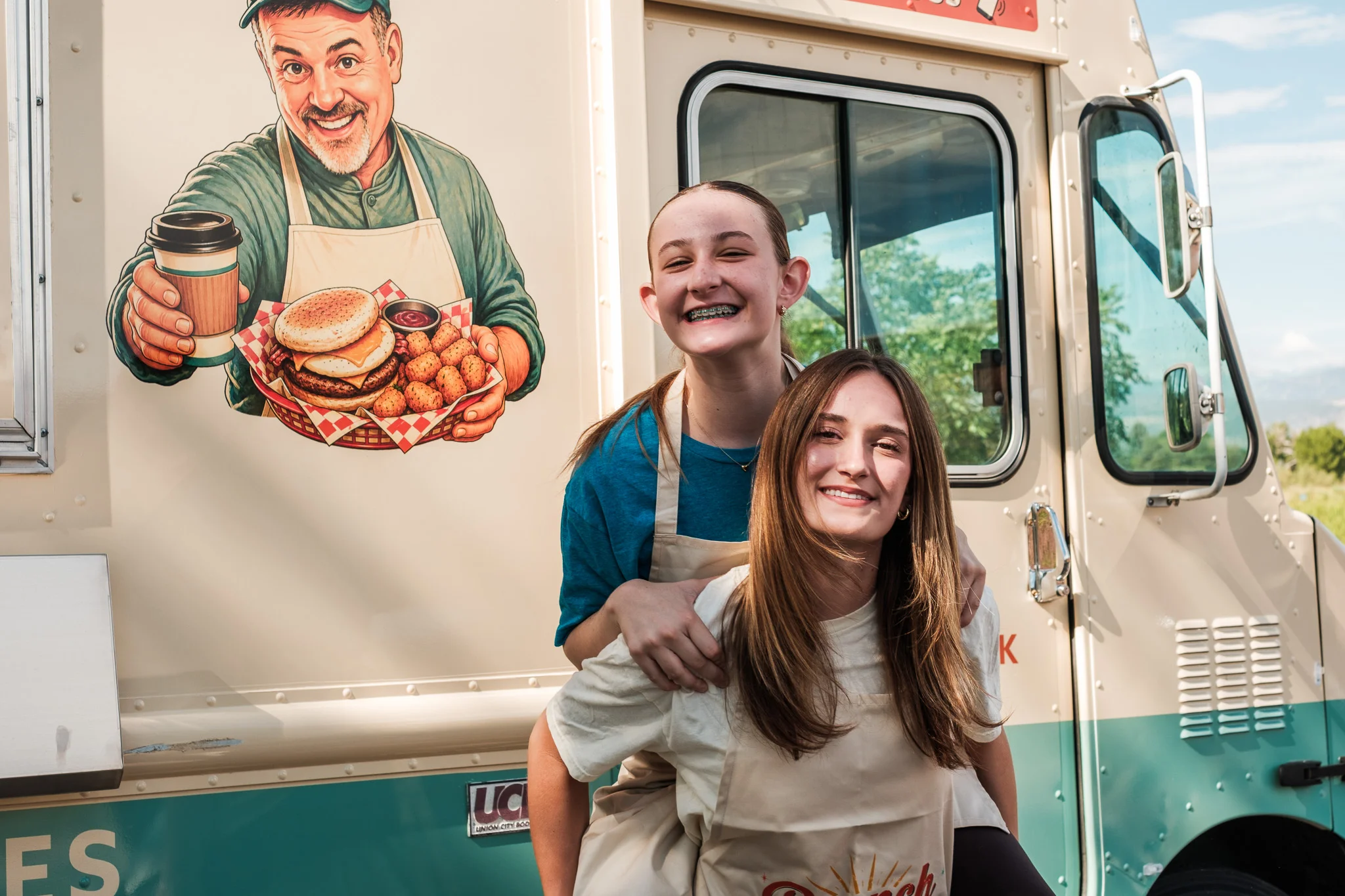 Food truck with smiling staff and a burger illustration