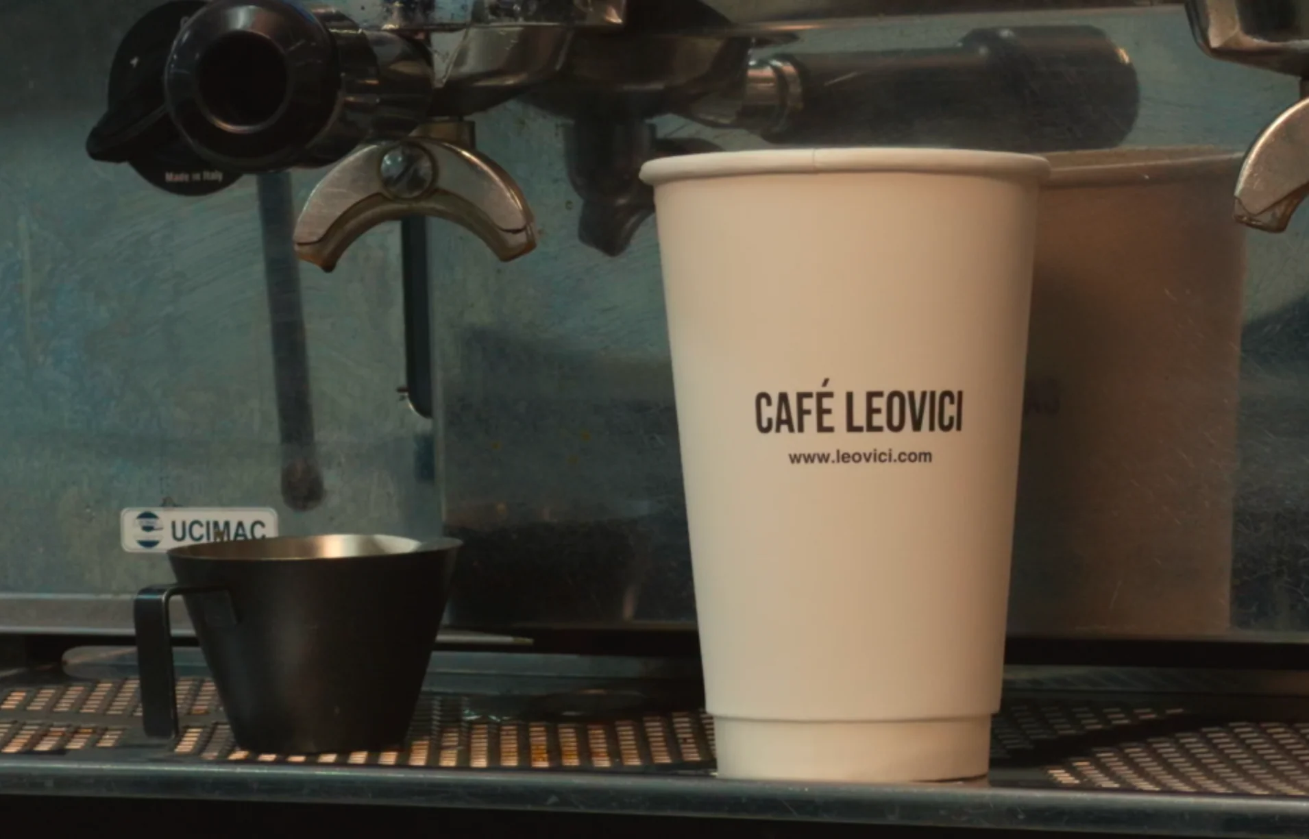 Café Leovici coffee cup beside espresso machine