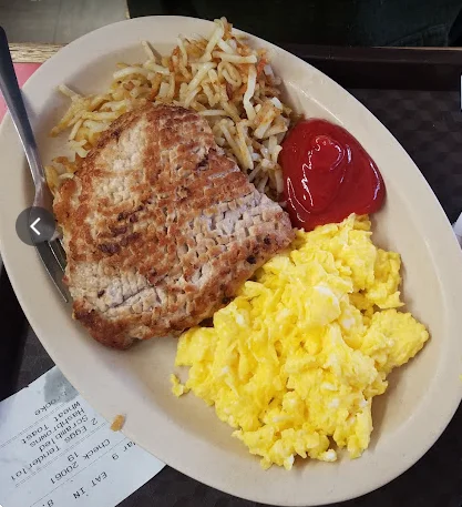 Classic American breakfast plate with eggs, hash browns, and grilled meat