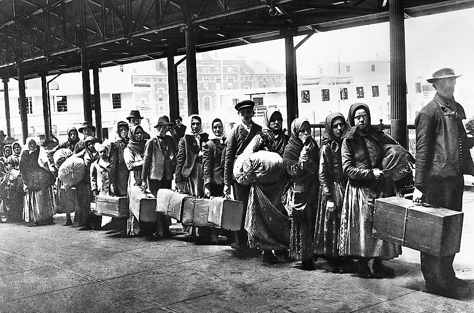 Historical image of immigrants arriving with luggage at a train station