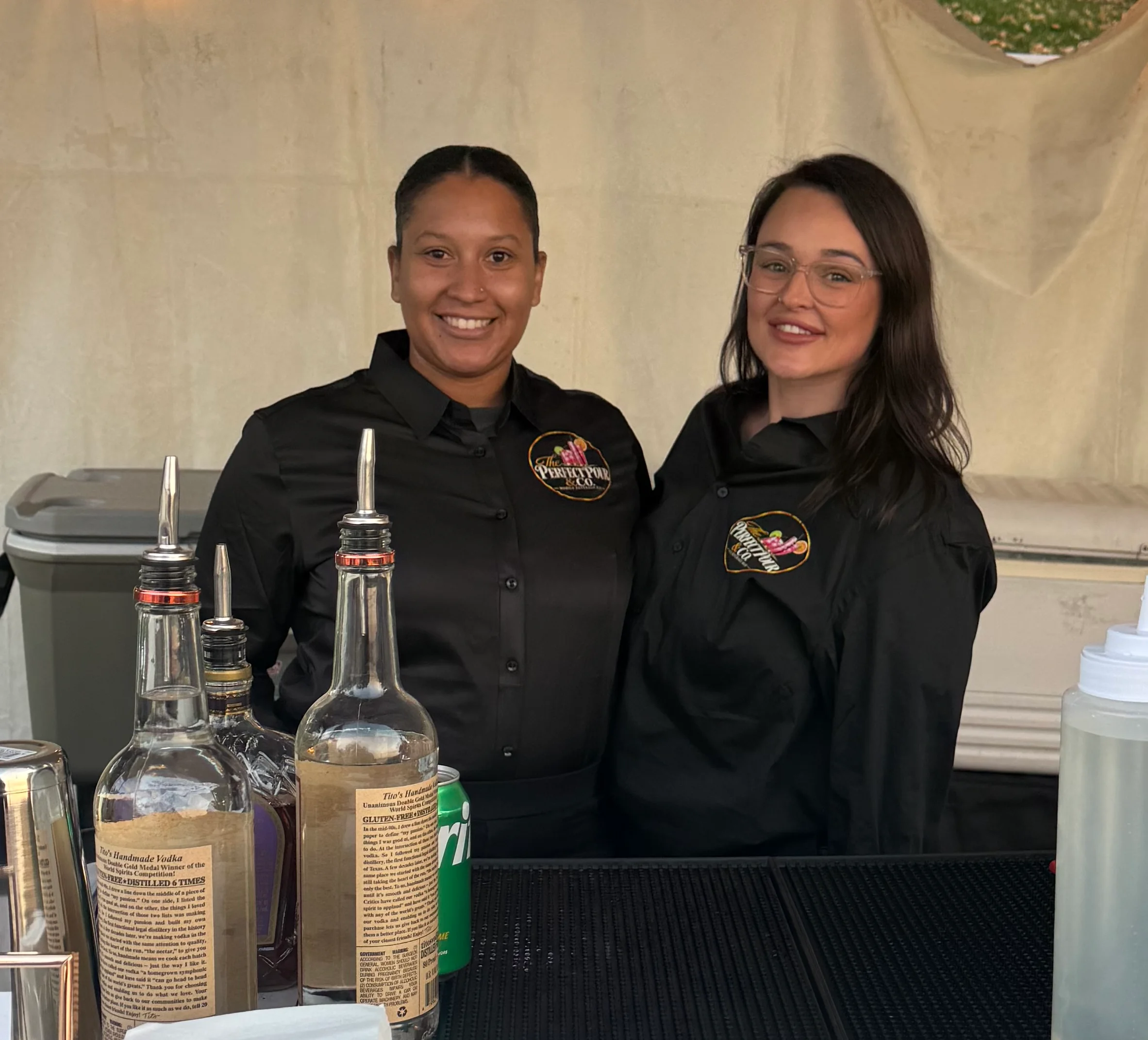 Bartenders serving drinks behind a restaurant bar with cocktail equipment