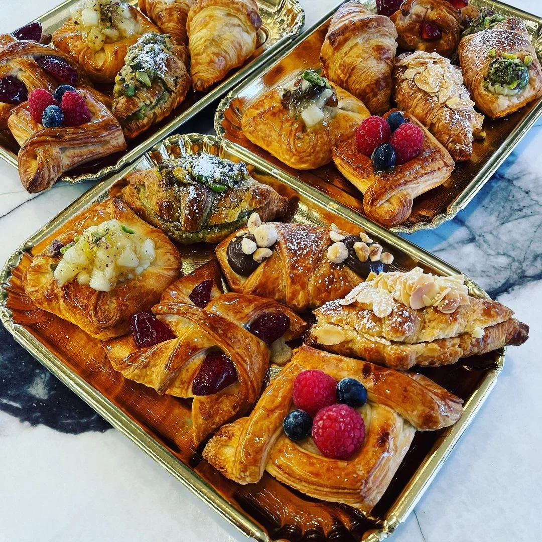 Assorted pastries on golden trays, featuring fruits and nuts.