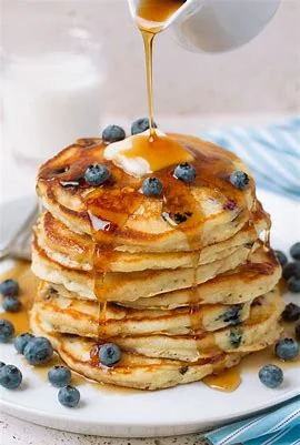 Fluffy blueberry pancakes drizzled with maple syrup