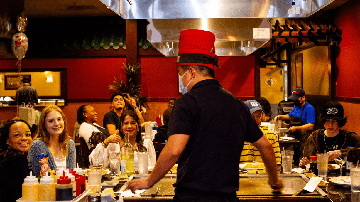 Guests smiling around a hibachi table during a party at Mahzu East Windsor