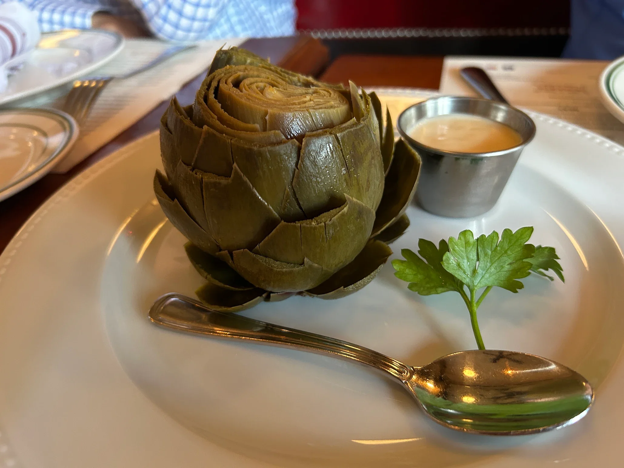 Steamed artichoke served with dipping sauce in a restaurant setting