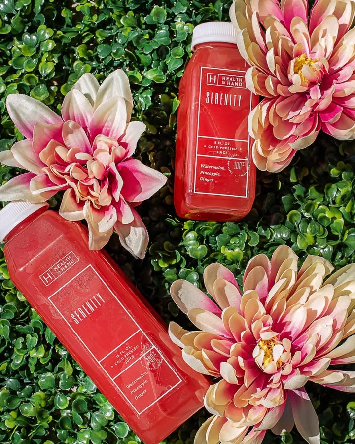 Refreshing cold-pressed juice bottles surrounded by vibrant flowers