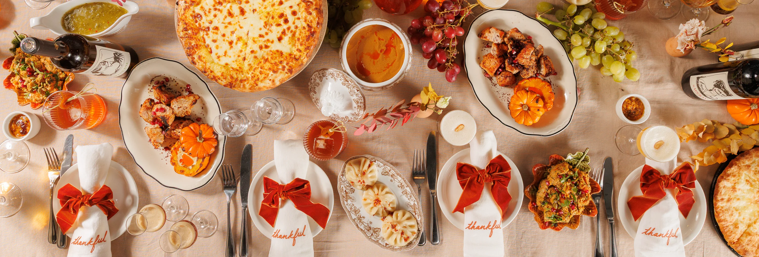 Festive Thanksgiving dinner table with cheese bread, dumplings, wine, and seasonal decor