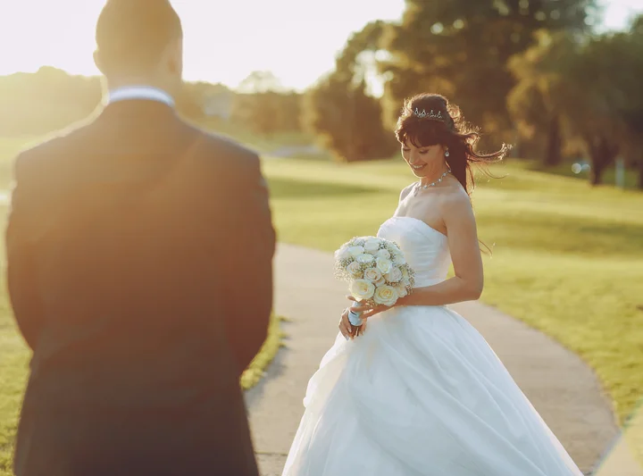 Bride in a wedding dress holding bouquet at sunset