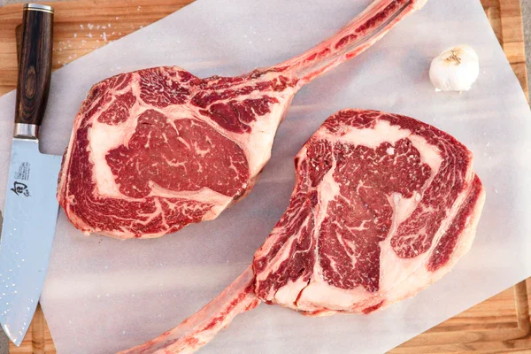 Two tomahawk steaks ready for grilling