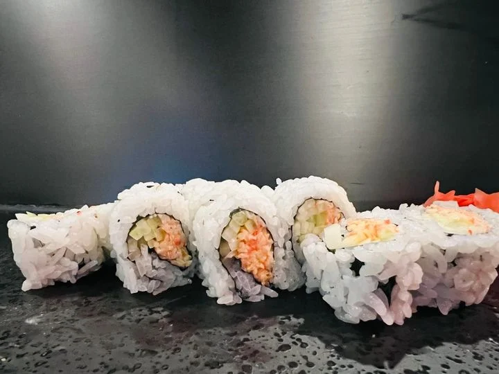 A selection of sushi rolls featuring rice and various fillings, neatly arranged on a dark surface.