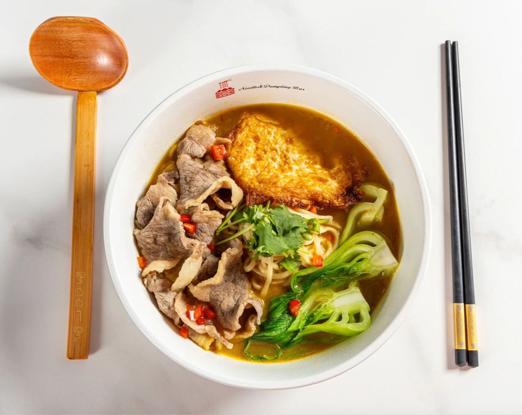 Savory bowl of Chinese beef noodle soup with greens and egg