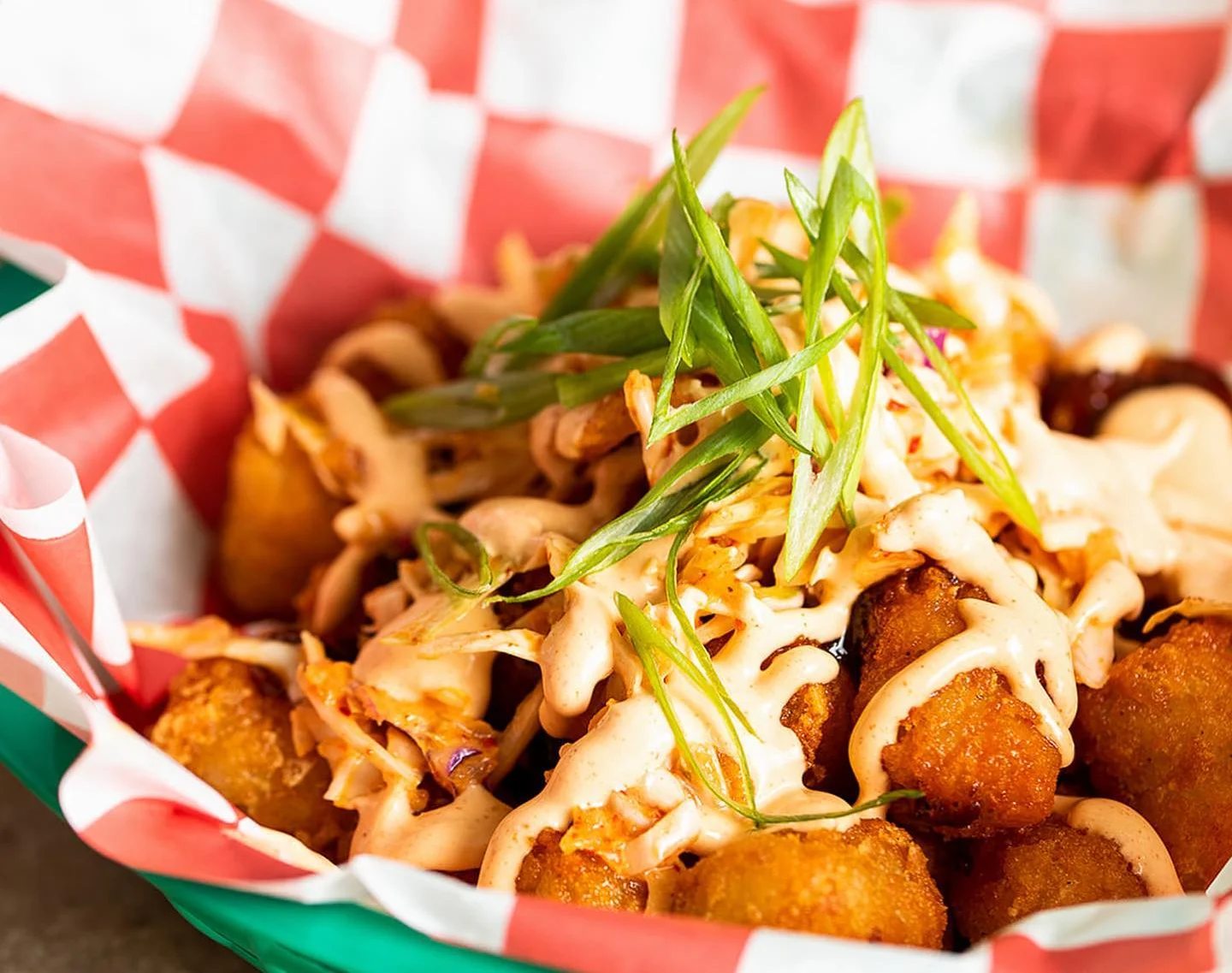 Crispy tater tots topped with spicy sauce and green onions