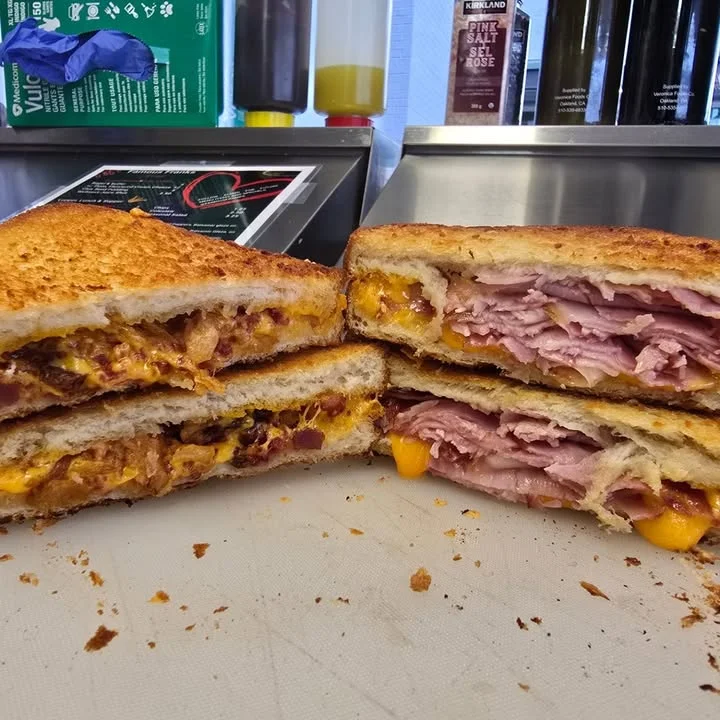Two halves of grilled sandwiches, one filled with melted cheese and the other with ham and cheddar, showcasing a golden-brown crust.