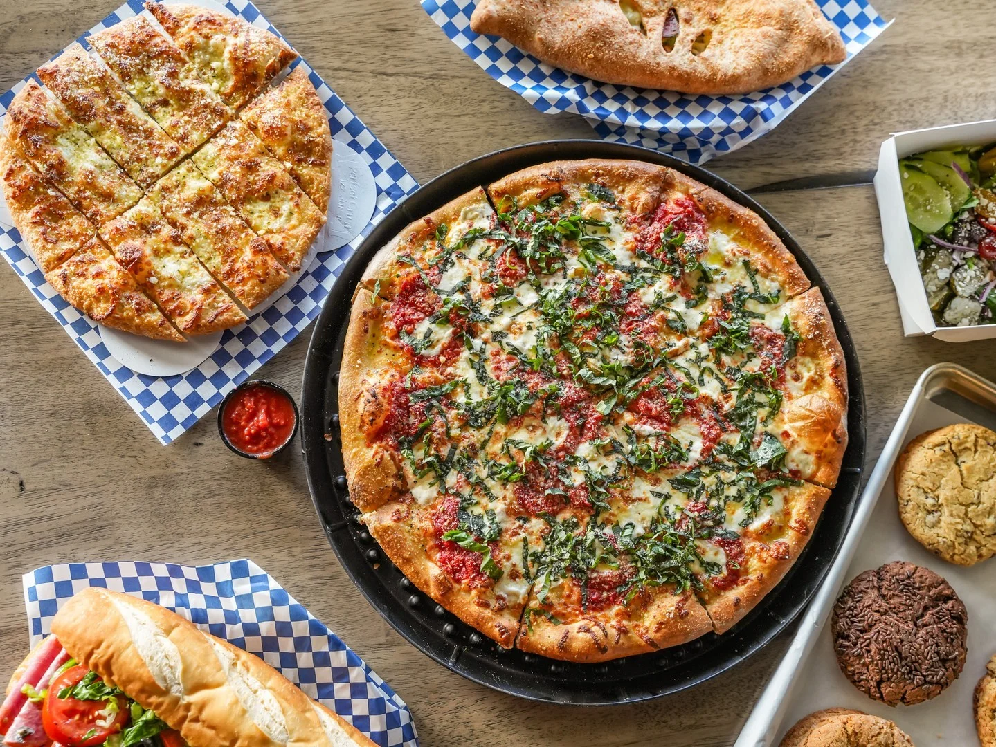 Delicious pepperoni pizza with fresh basil and garlic bread on a wooden table