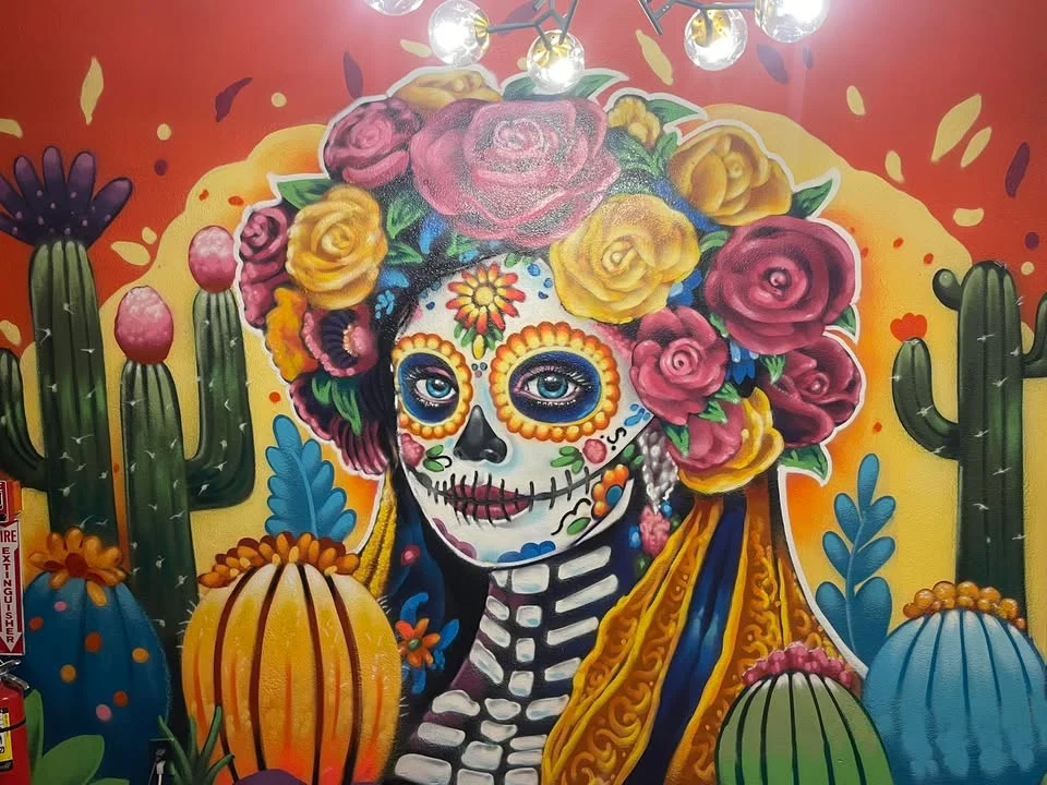 A vibrant mural depicting a decorated skull surrounded by colorful flowers and cacti.