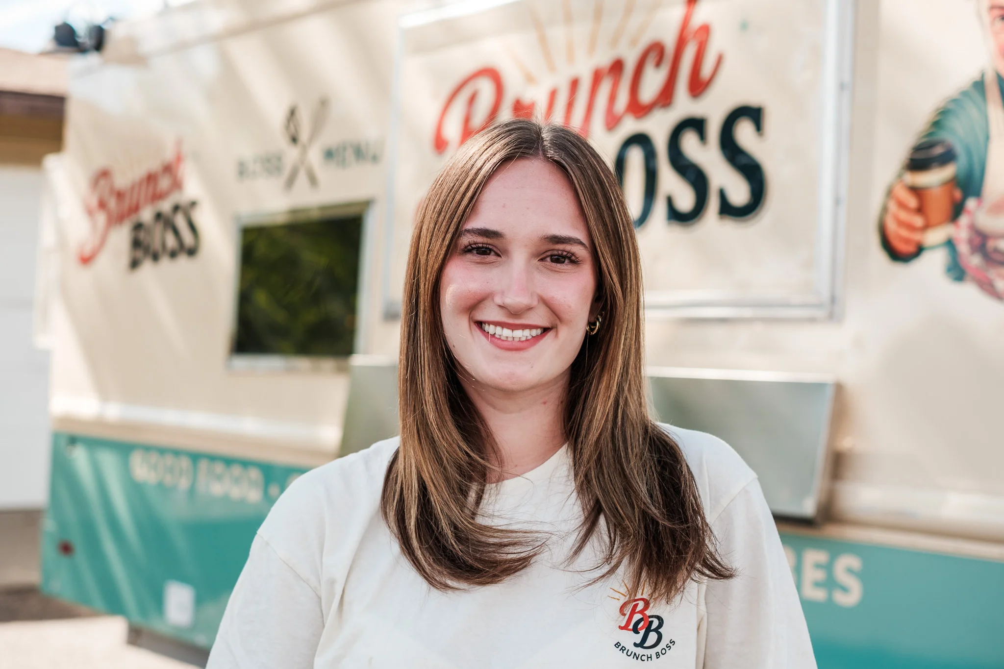 Smiling woman in front of a food truck named Brunch Boss
