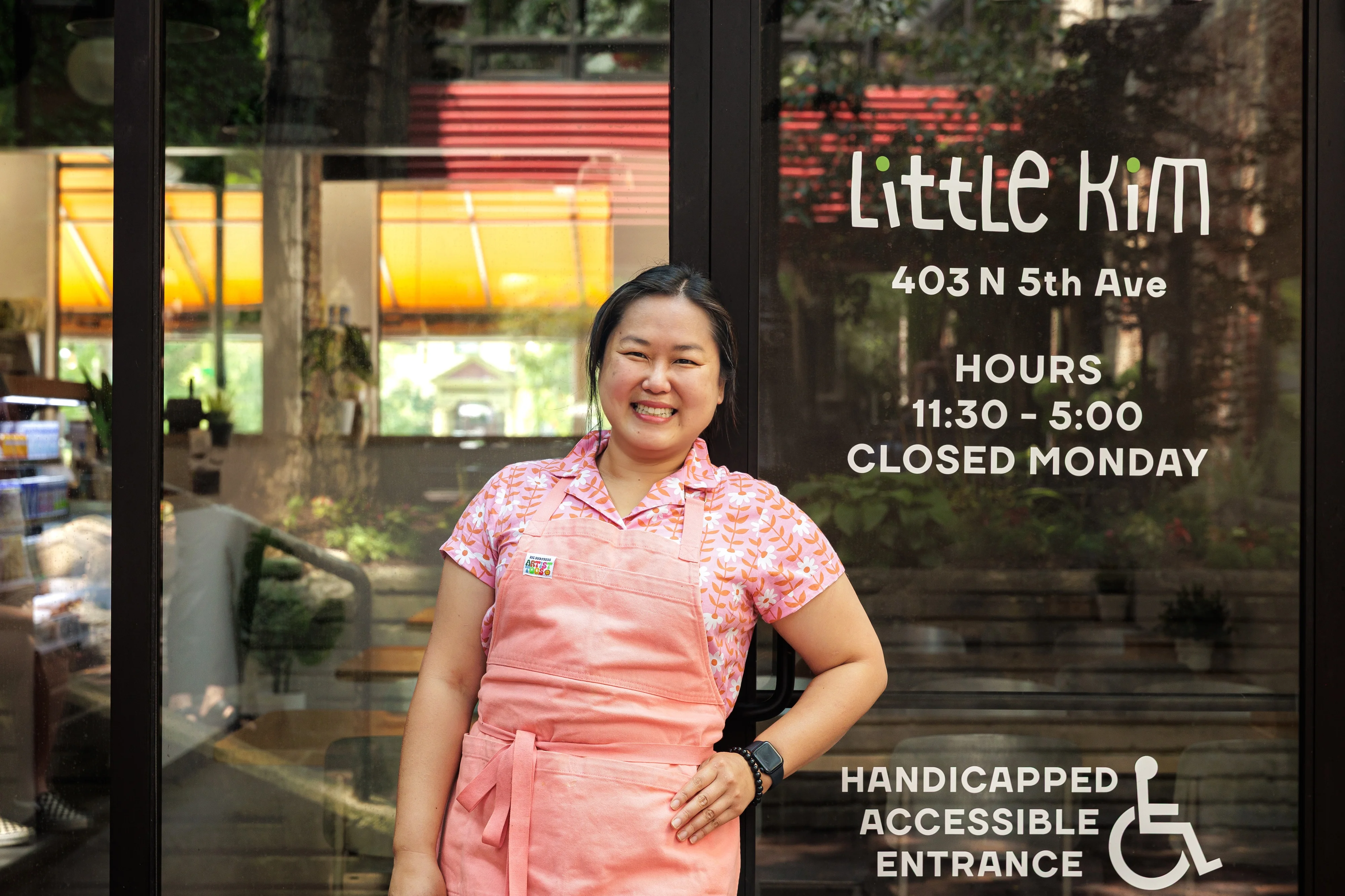 Owner smiling outside Little Kim restaurant with accessible entrance