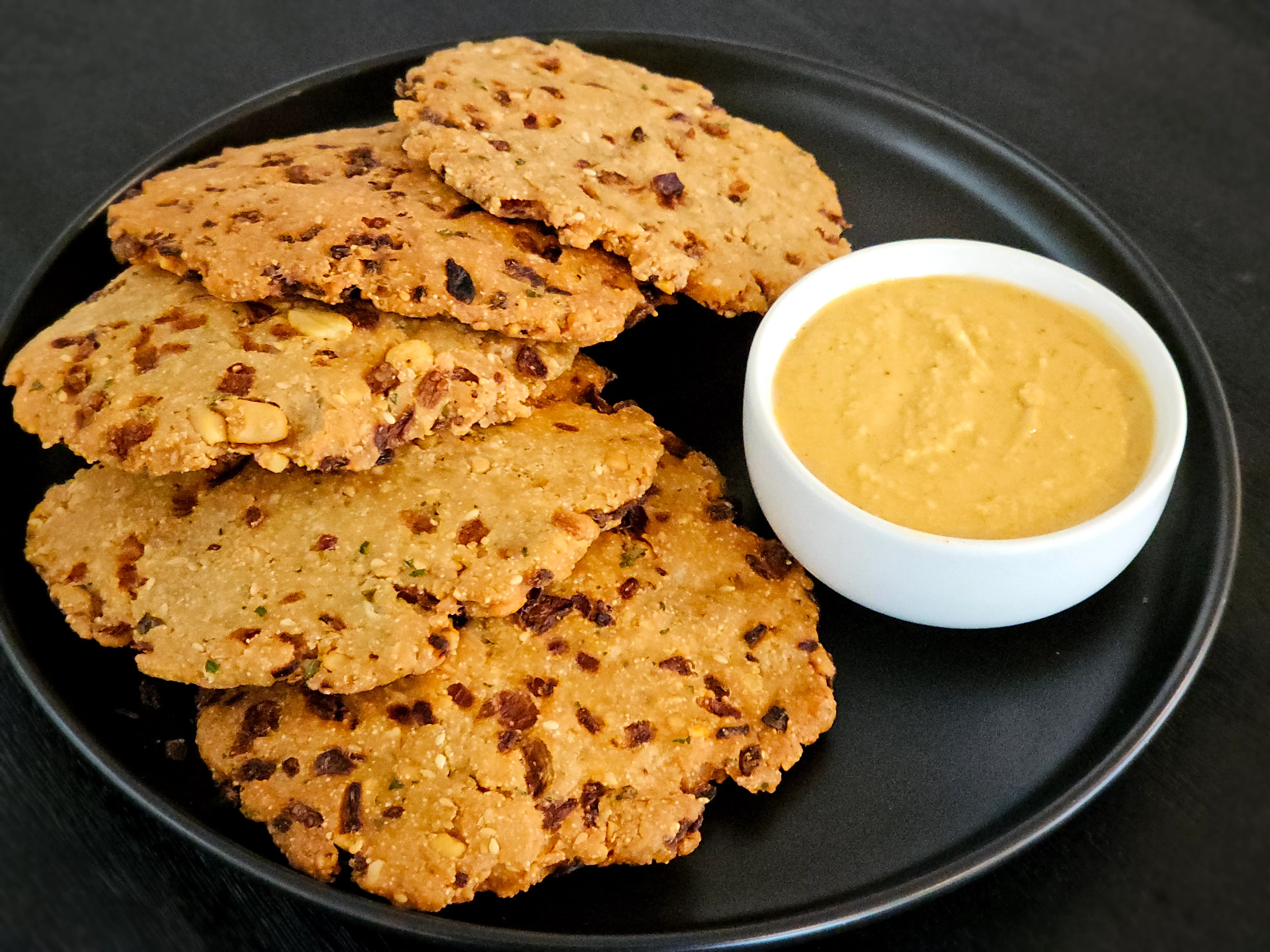 Indian khakra served with chutney on a black plate