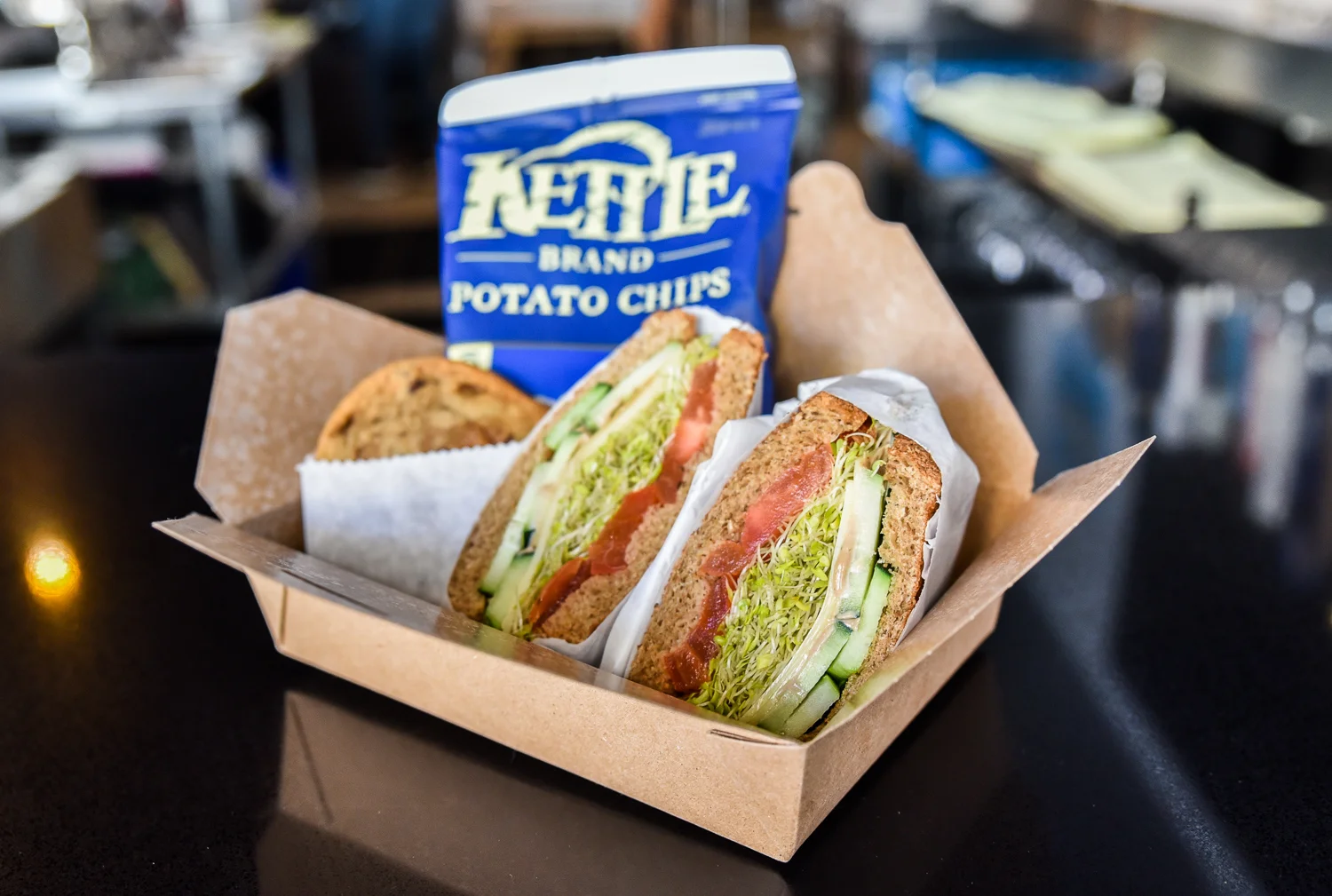Fresh deli sandwich with potato chips in a takeout box
