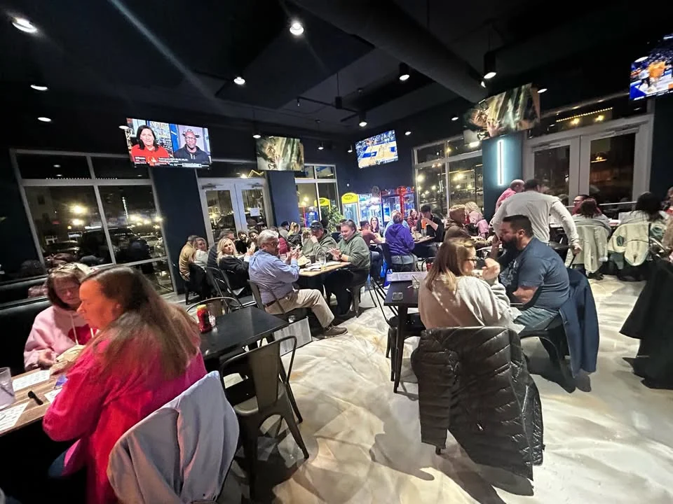 Lively restaurant interior with diners enjoying meals and sports on TV