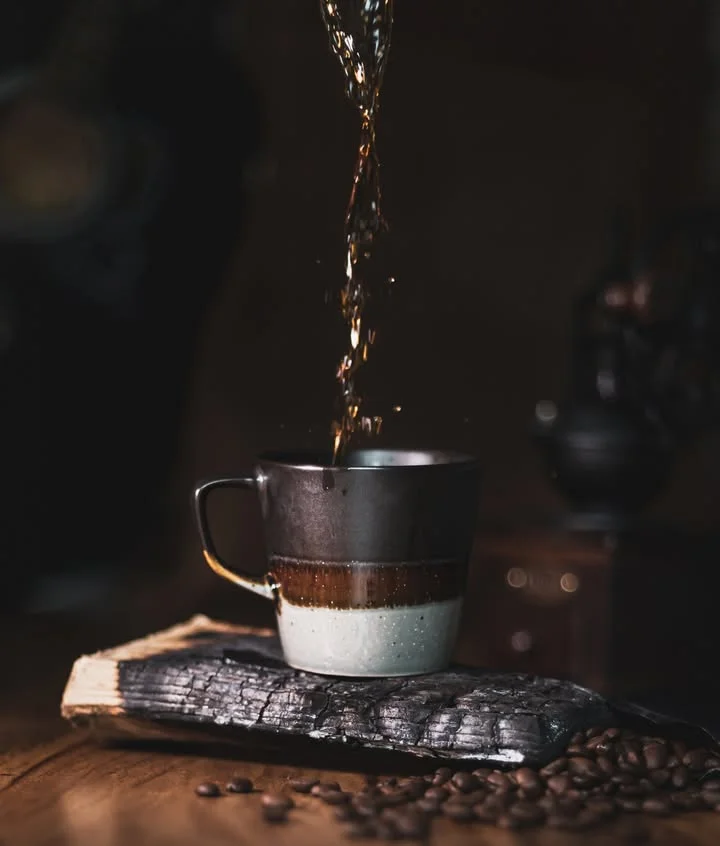 Pouring coffee into a rustic mug on a wooden surface