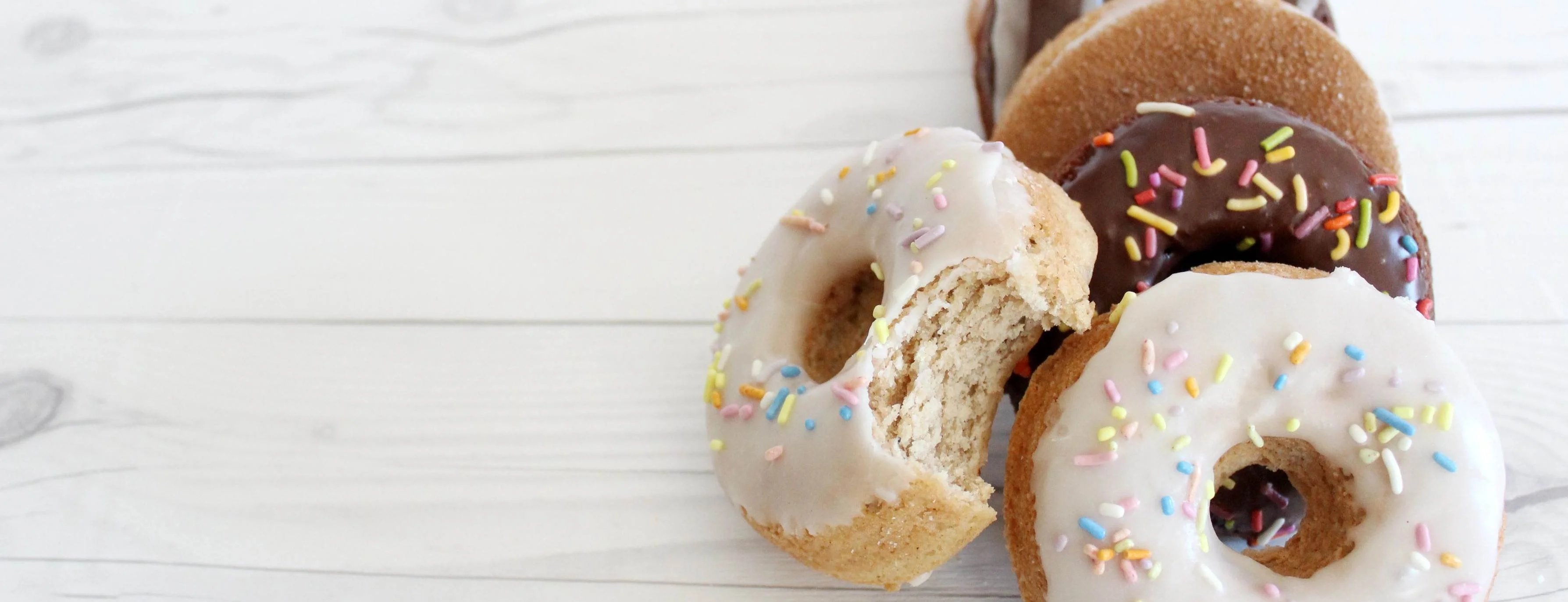 Assorted donuts with sprinkles on a wooden table