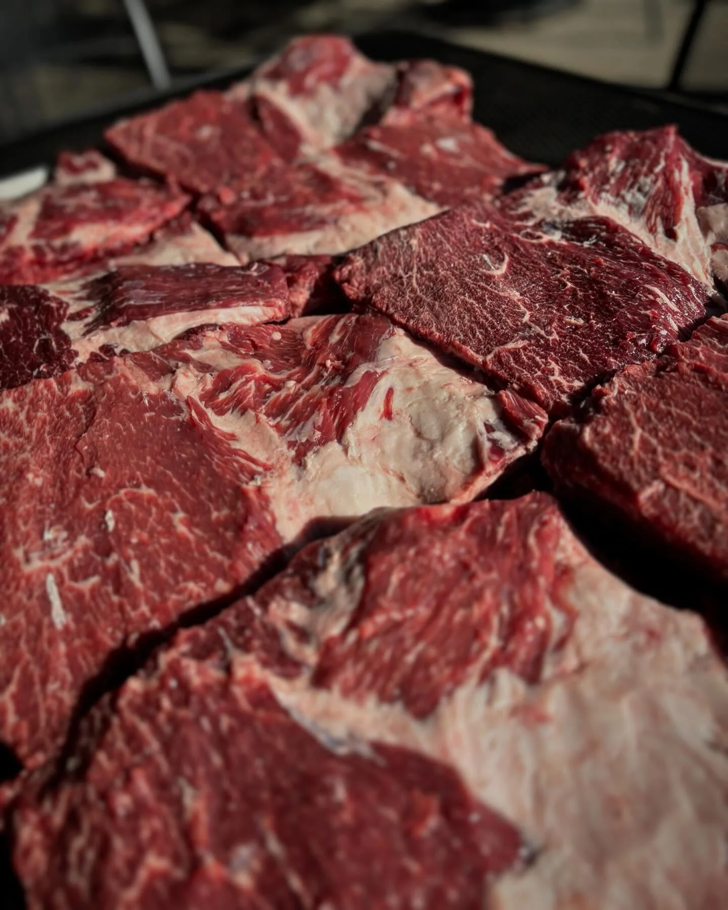 A close-up view of various pieces of raw meat, showcasing marbling and texture.