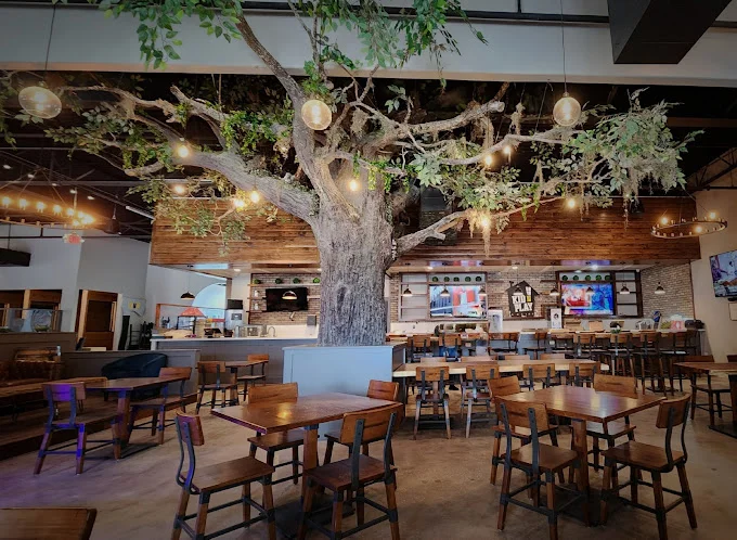 Interior of a restaurant featuring a large tree and wooden furniture.