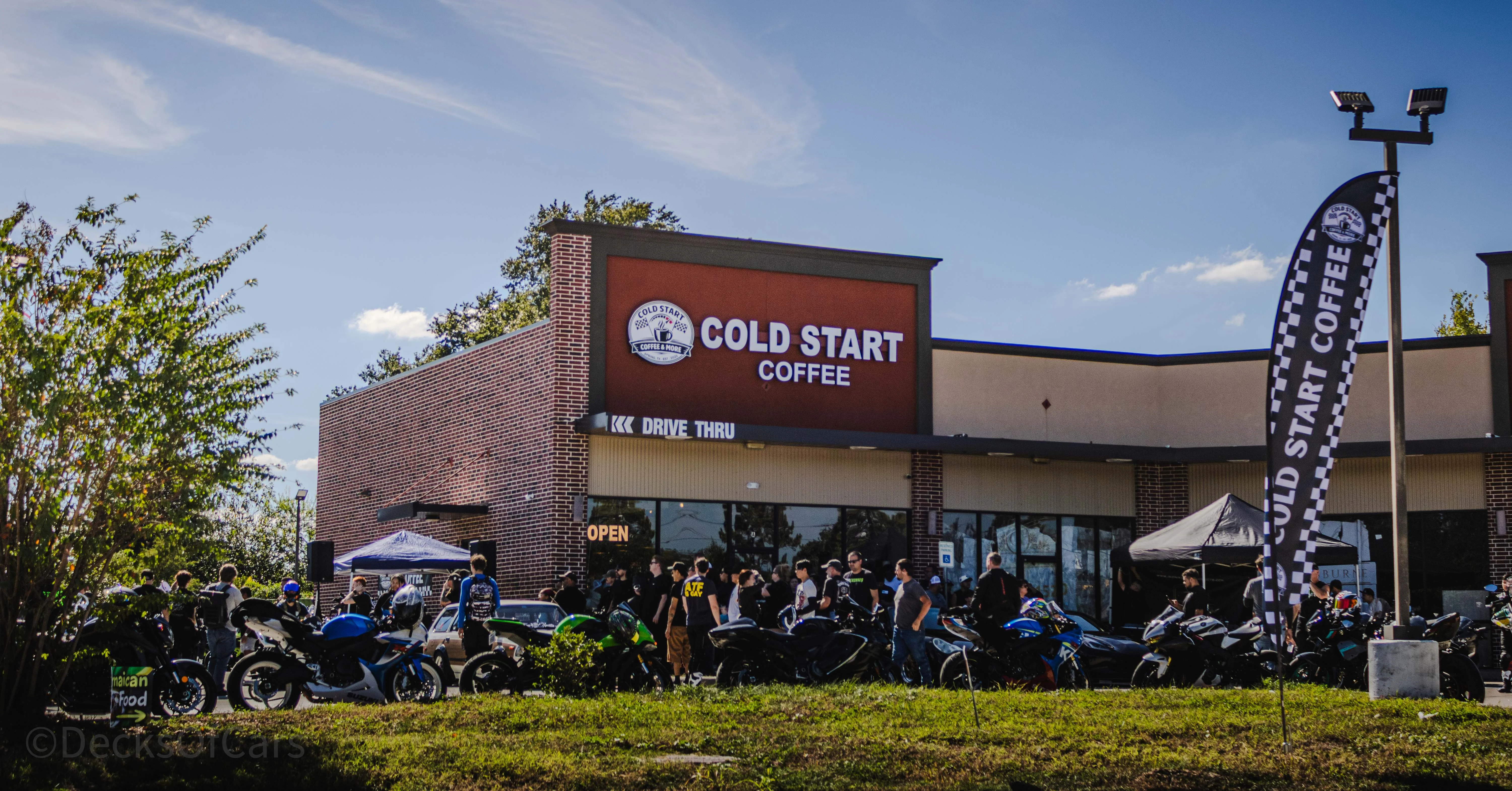 Outdoor coffee shop exterior with checkered flags and cyclists