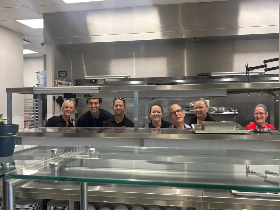 Cheerful kitchen staff posing in a modern restaurant kitchen