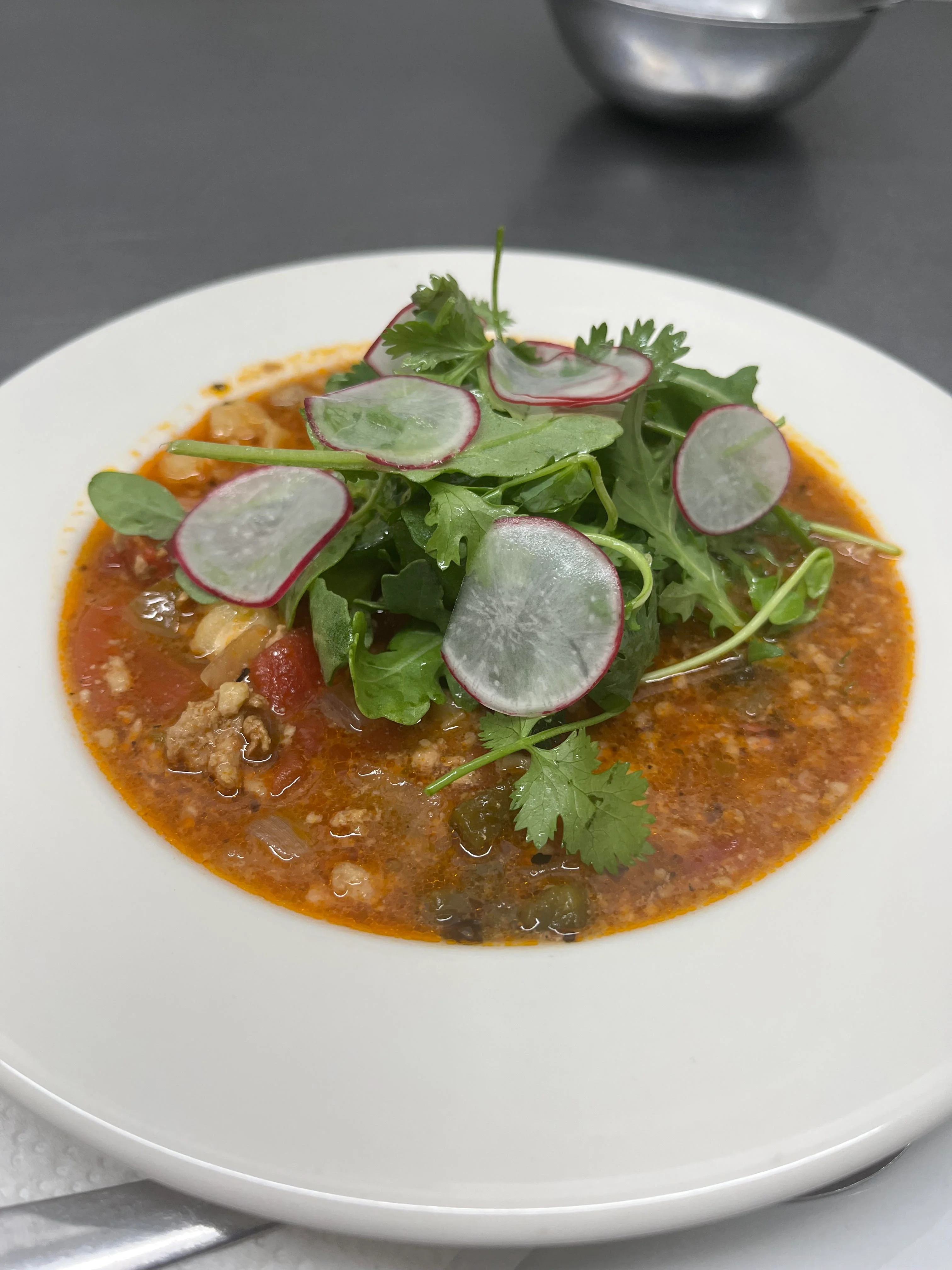 Hearty Mexican pozole topped with fresh herbs and radishes