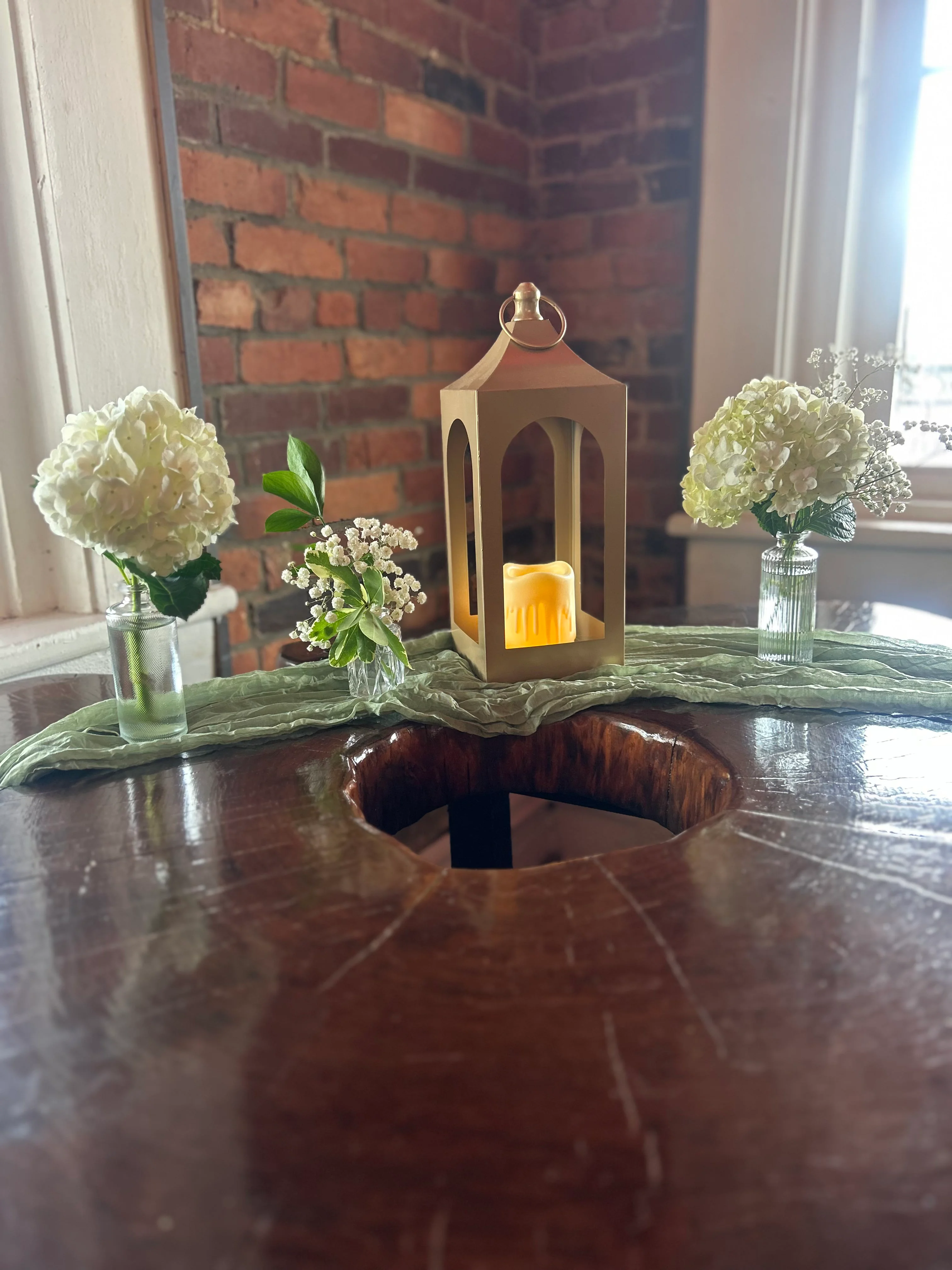 A rustic table centerpiece featuring a lantern surrounded by white flowers in vases, creating a charming atmosphere.