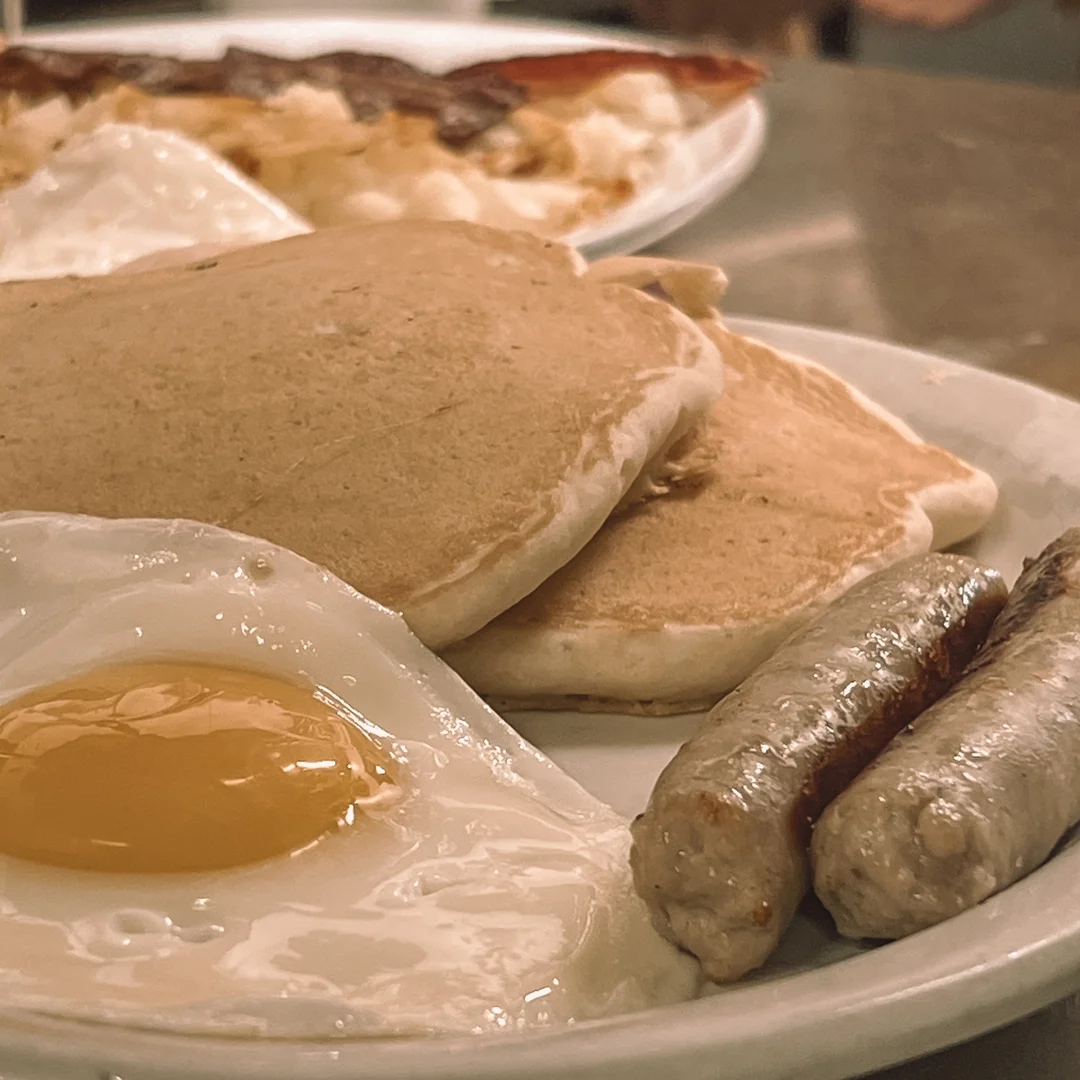 Classic American breakfast with pancakes, eggs, and sausage