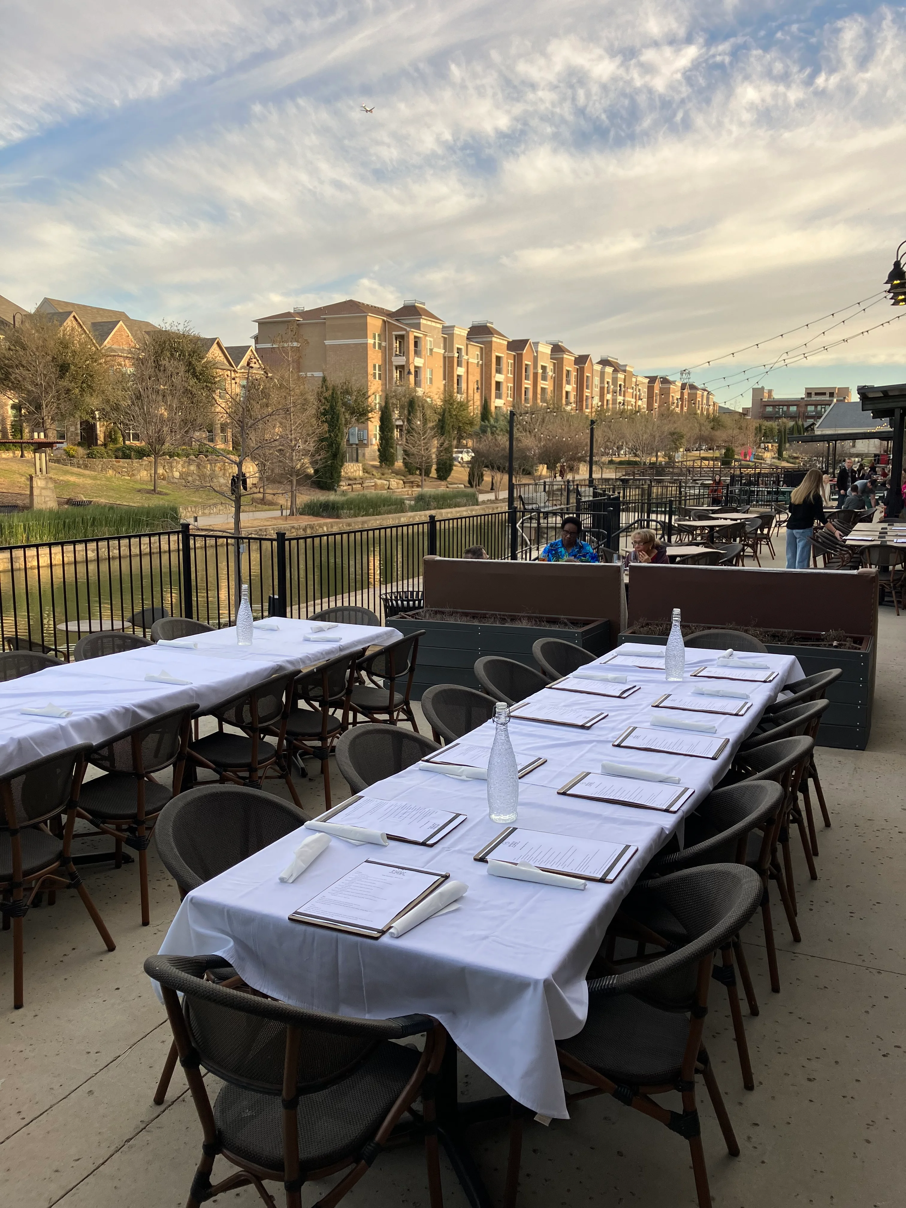 Outdoor dining setup by the water with elegant tables and chairs
