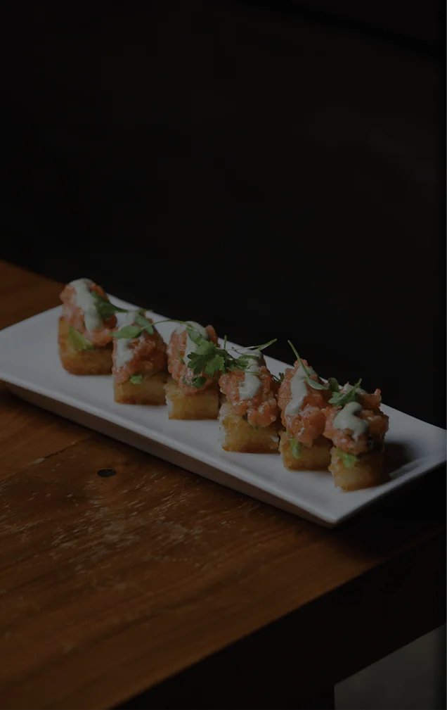 Five pan-seared pork or vegetable dumplings garnished with microgreens, served on a white rectangular plate.