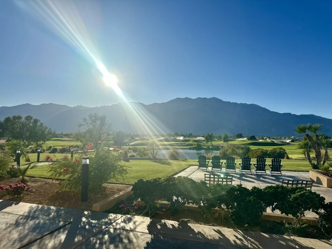 Scenic view of mountains and golf course under bright sun