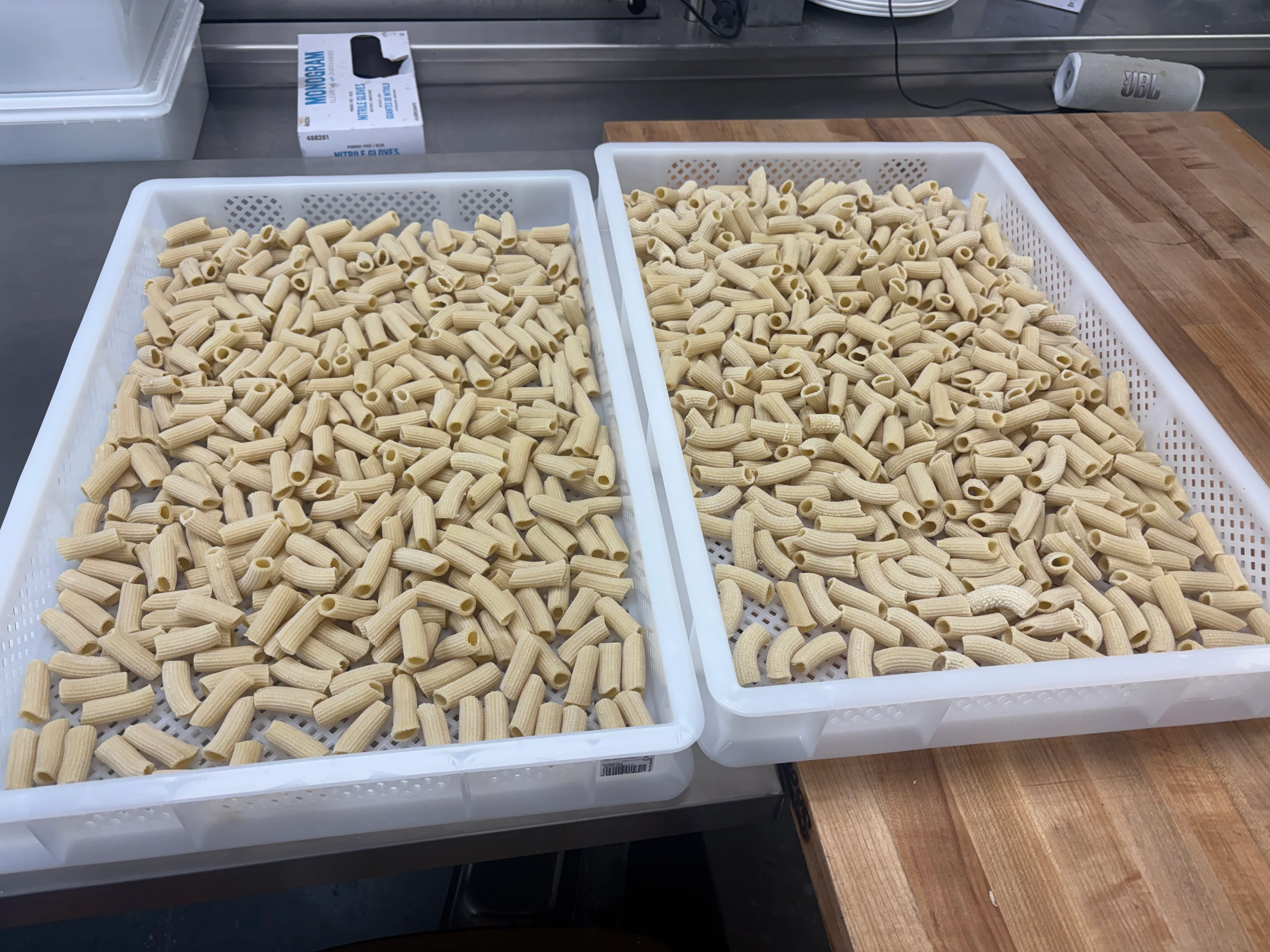 Uncooked Italian rigatoni pasta arranged in white kitchen baskets